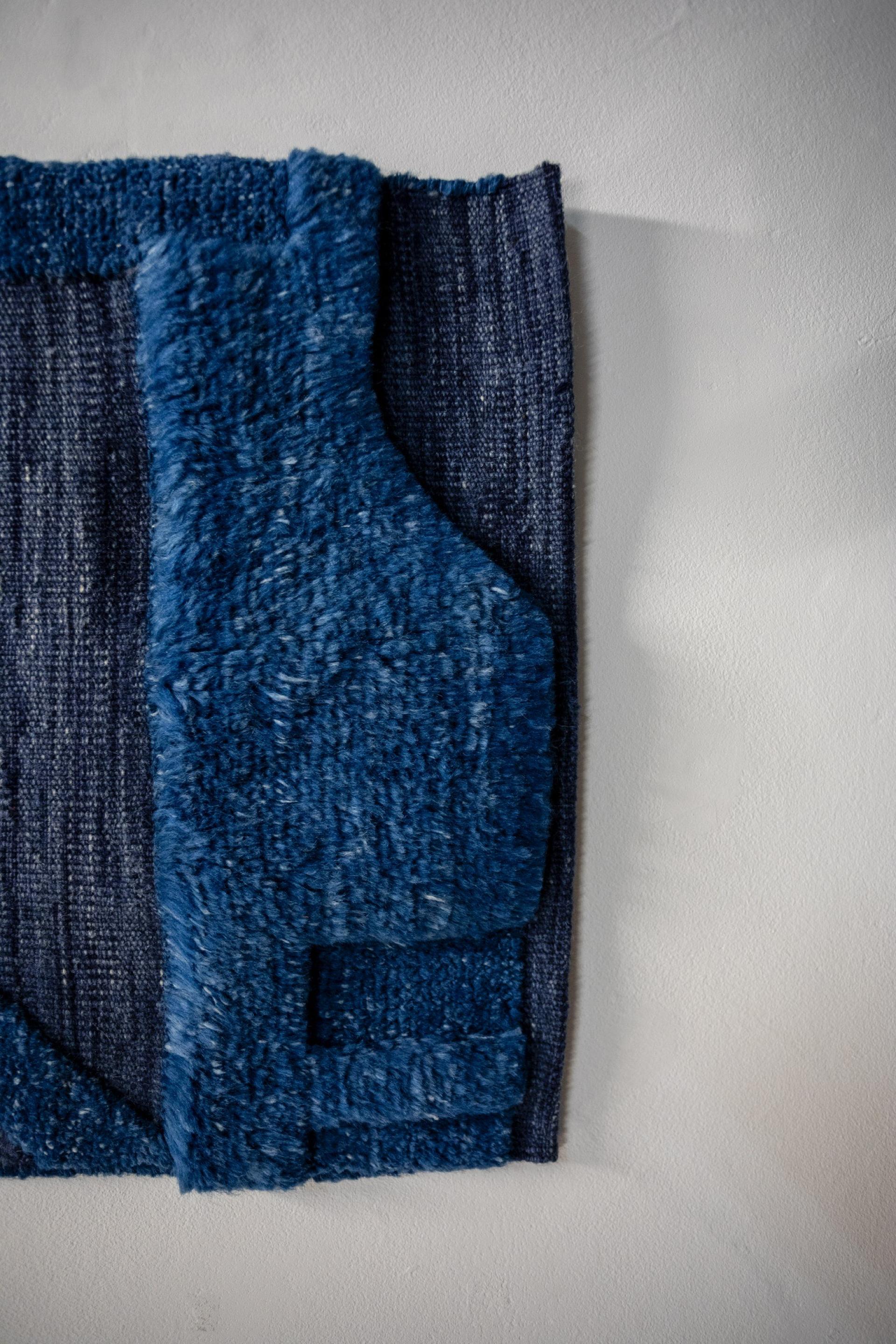 Textile art piece featuring layered blue fabrics, highlighting the narrative of memory and material in Dharma Taylor's exhibition.