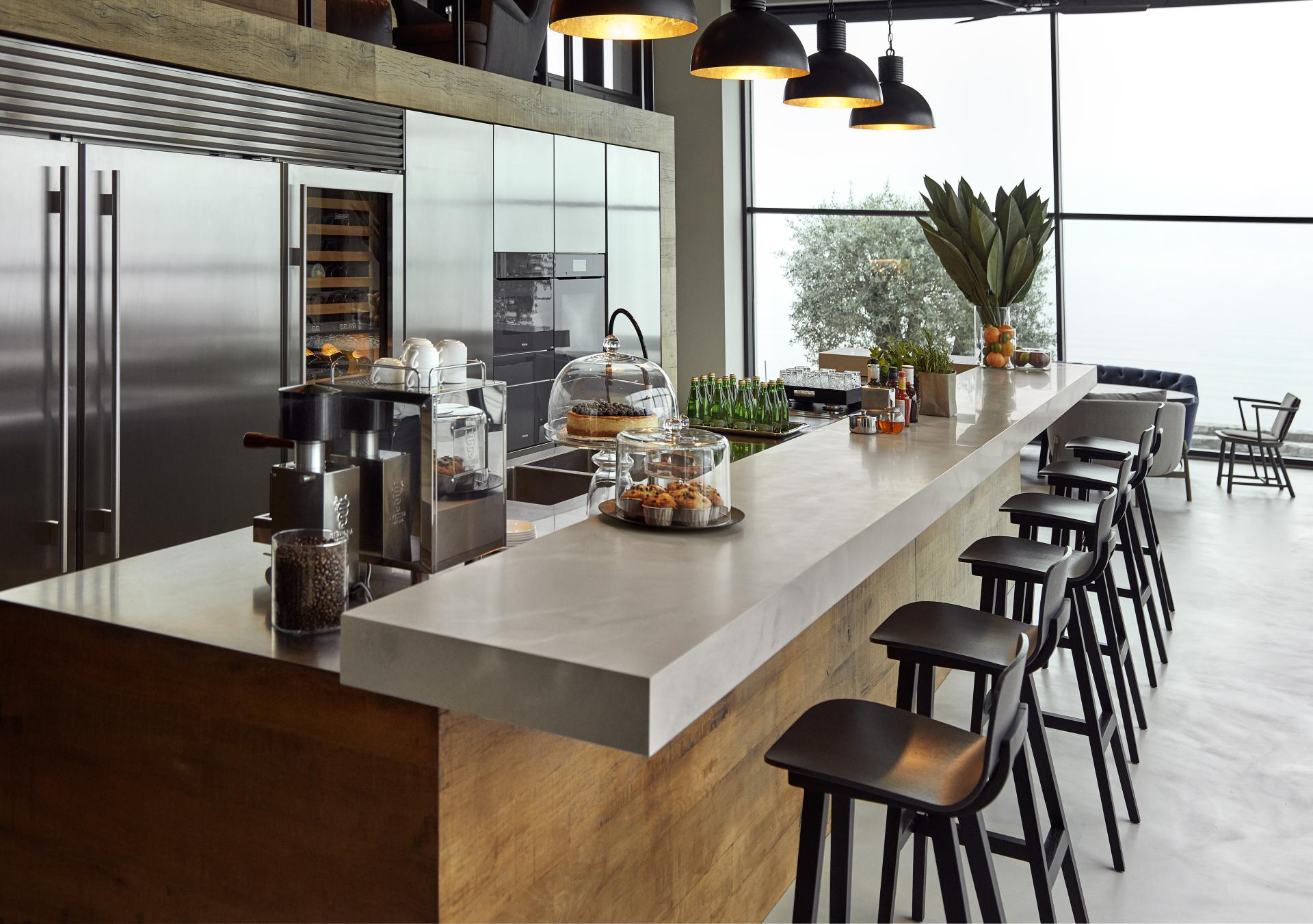 Modern kitchen featuring new Corian countertops, stylish bar stools, and a variety of refreshments, emphasizing elegance and functionality.