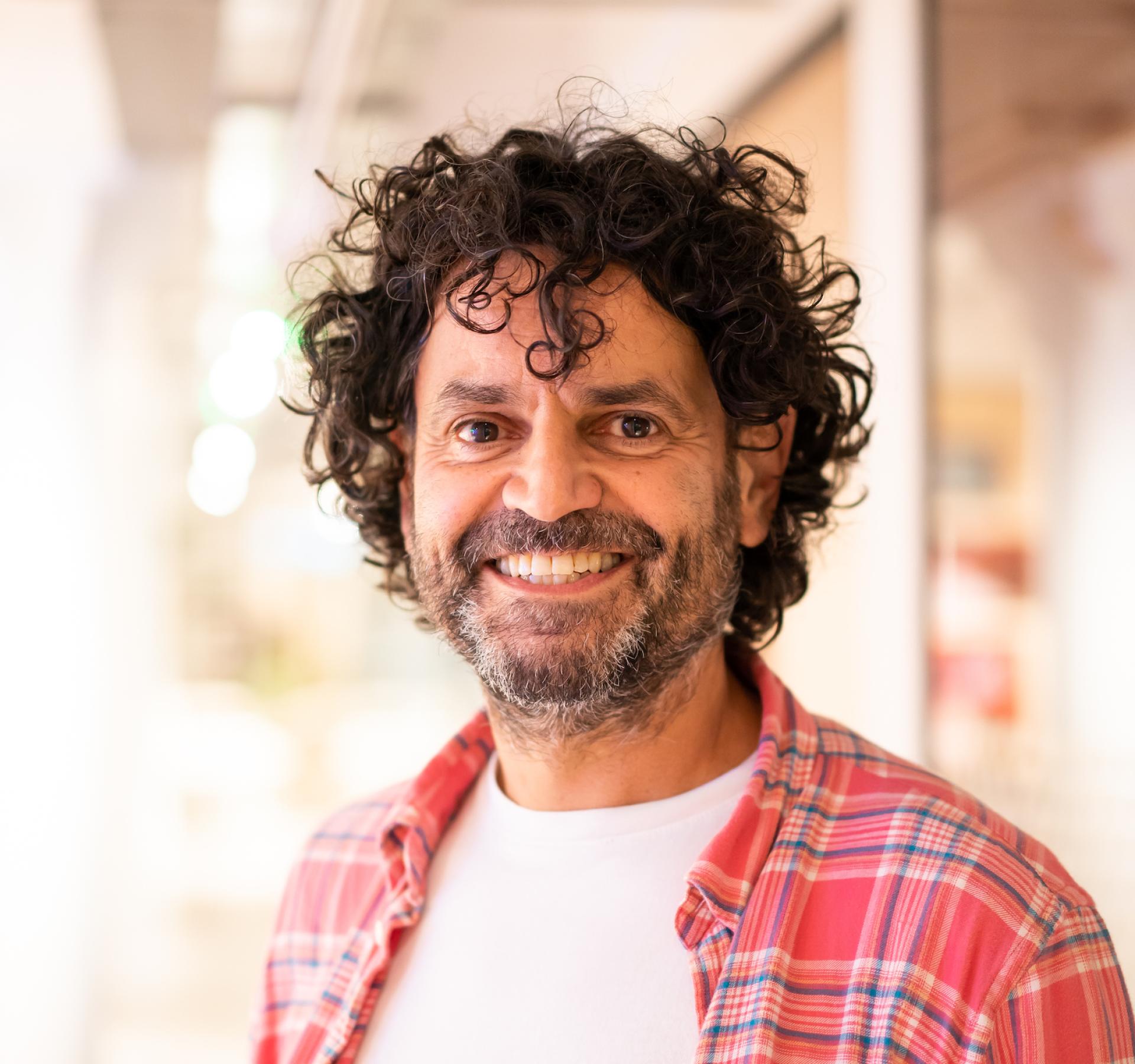 Smiling educator with curly hair in a modern learning environment, reflecting the evolving future of education.