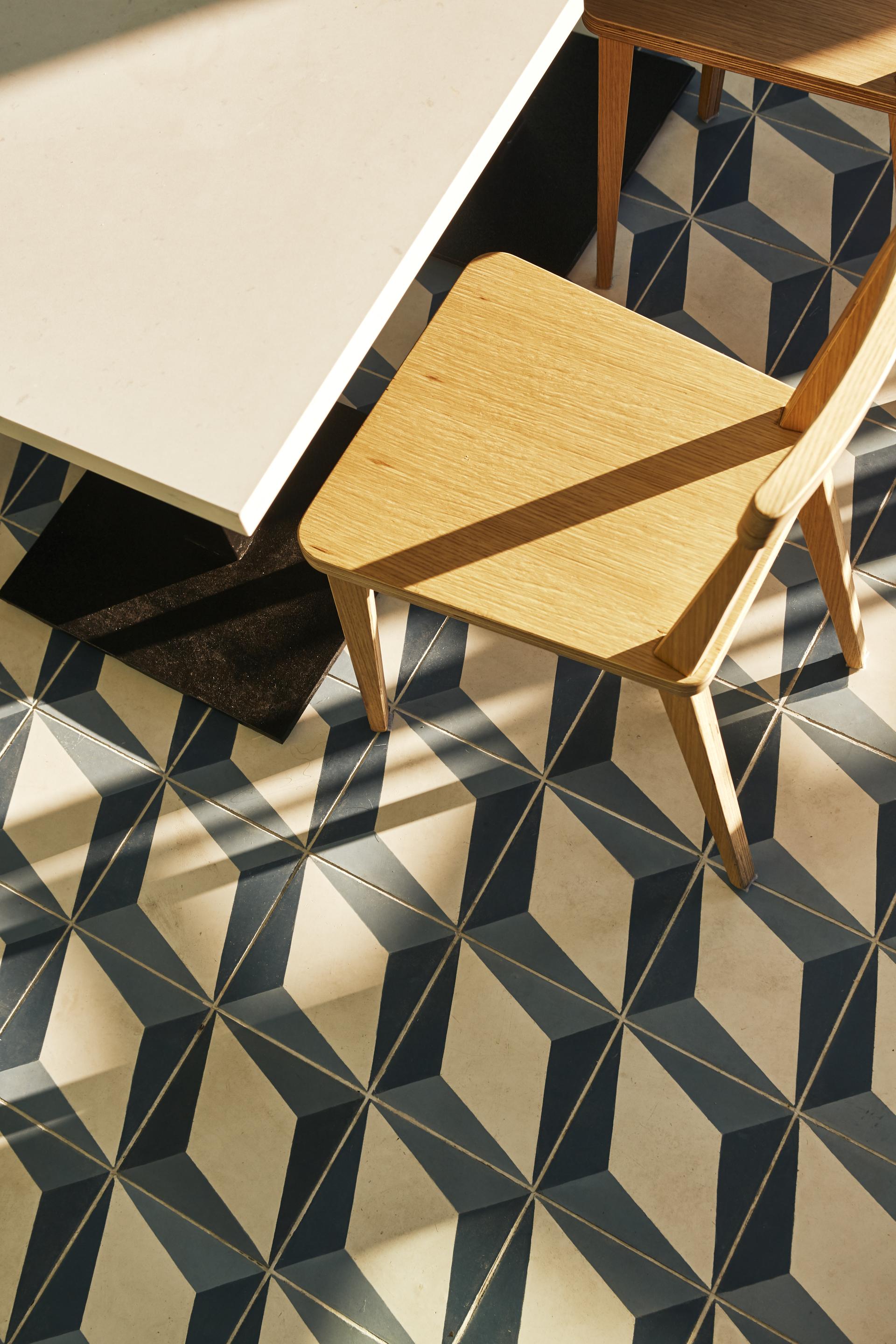 Stylish wooden chair beside a Caesarstone table on a patterned tile floor in a coffee space.