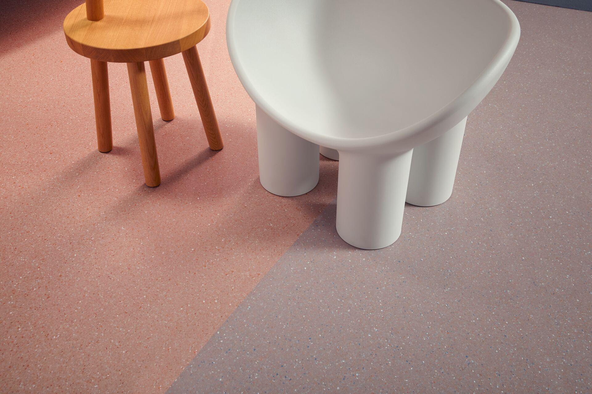Homogeneous vinyl flooring in a healthcare setting, featuring a wooden stool and a stylized white chair design.