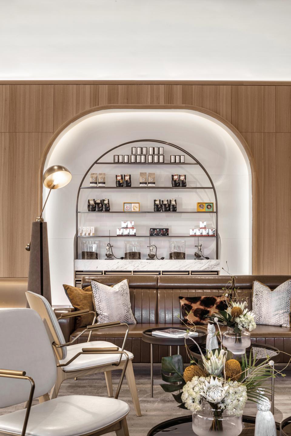 Stylish coffee shop interior featuring elegant seating, decorative pillows, and a display of coffee products on shelves.