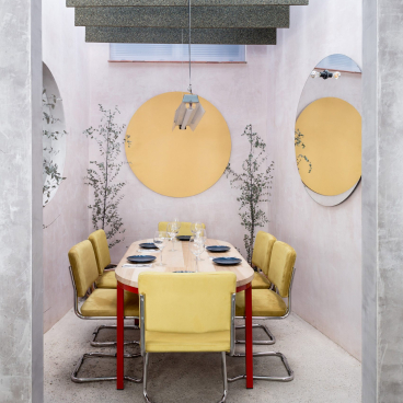 Interior design of a Seville restaurant featuring a concrete structure, pastel walls, yellow furniture, and unique lighting.