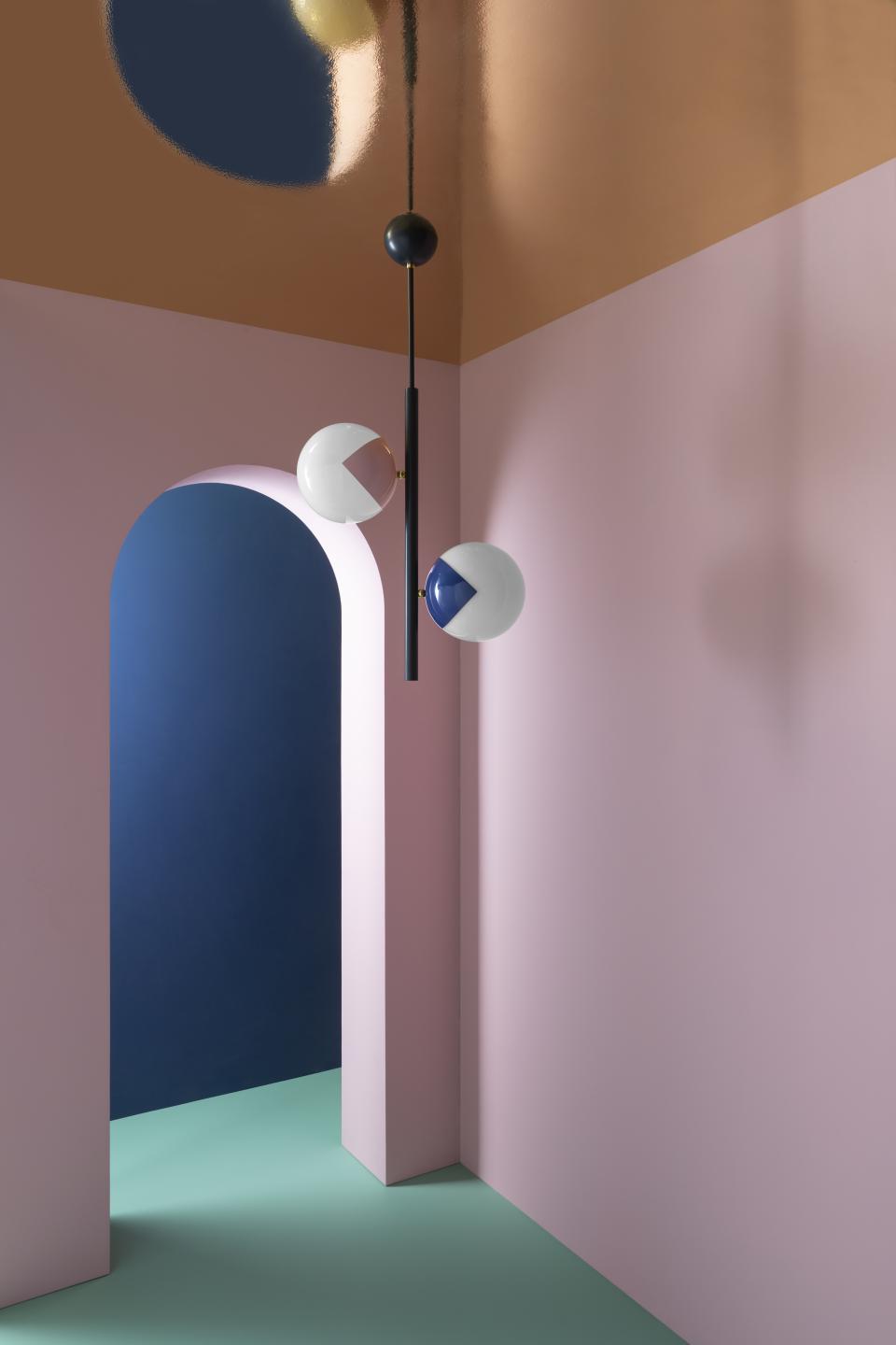 Colorful 'eyeball' lamps on a sleek black stem, set against a pastel background in a modern interior design.