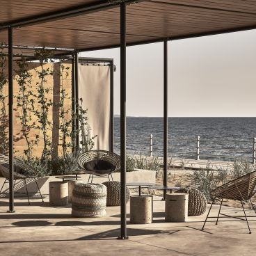 Chic outdoor seating area by the sea at a reimagined wine factory resort in Peloponnese, featuring modern design elements.