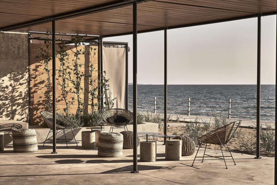 Chic outdoor seating area by the sea at a reimagined wine factory resort in Peloponnese, featuring modern design elements.