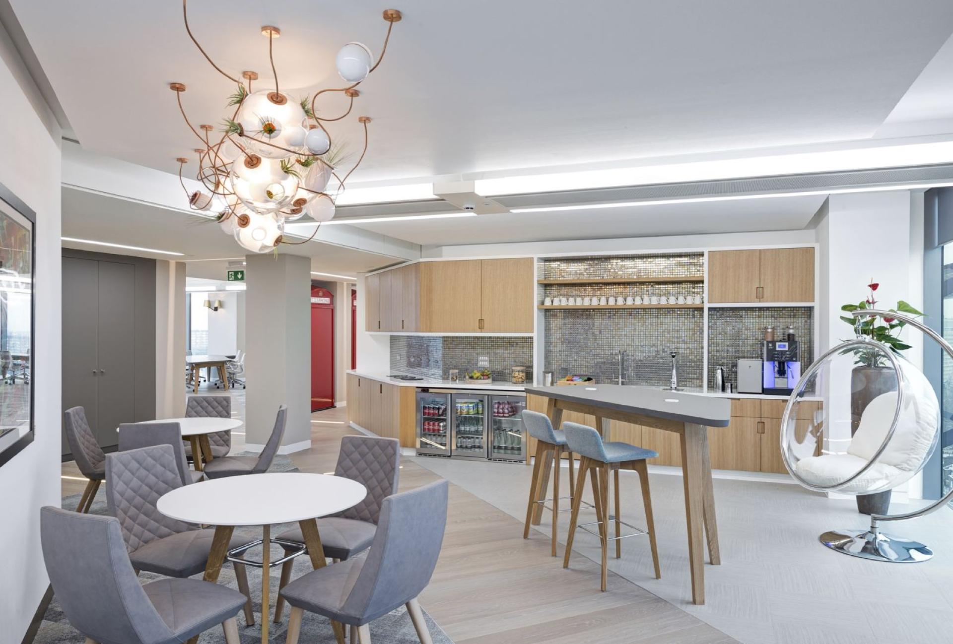 Modern workspace featuring stylish furniture, an open kitchen area, and unique lighting design for collaboration and creativity.