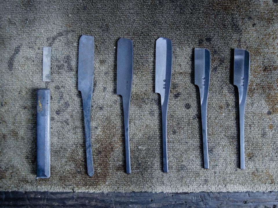 Traditional metal tools displayed on a craft surface, showcasing Tsubame-Sanjo's expert metal craftsmanship.