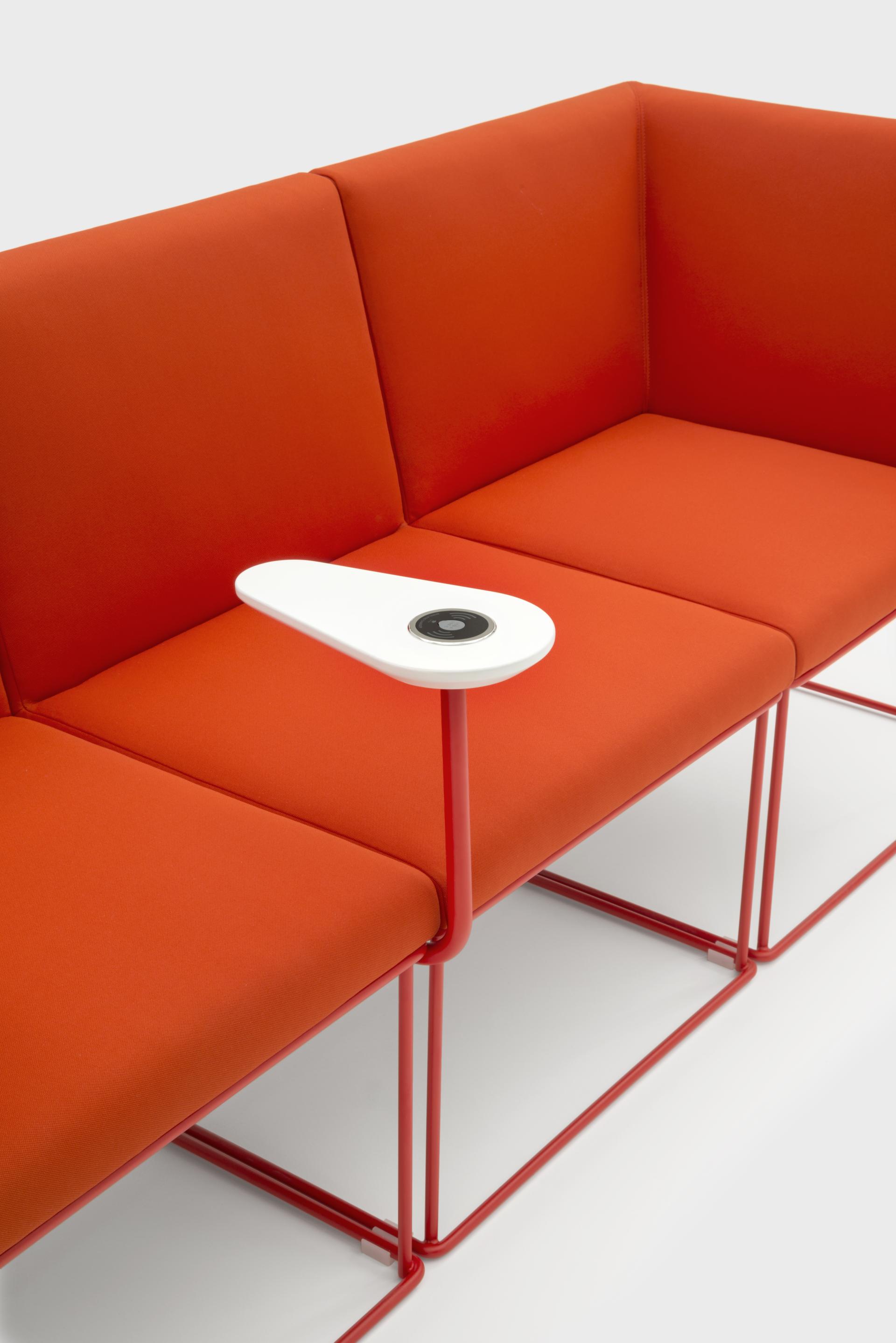 Modern orange sofa with a white armrest featuring a circular table, showcasing VIGANÒ & C.'s innovative design approach.