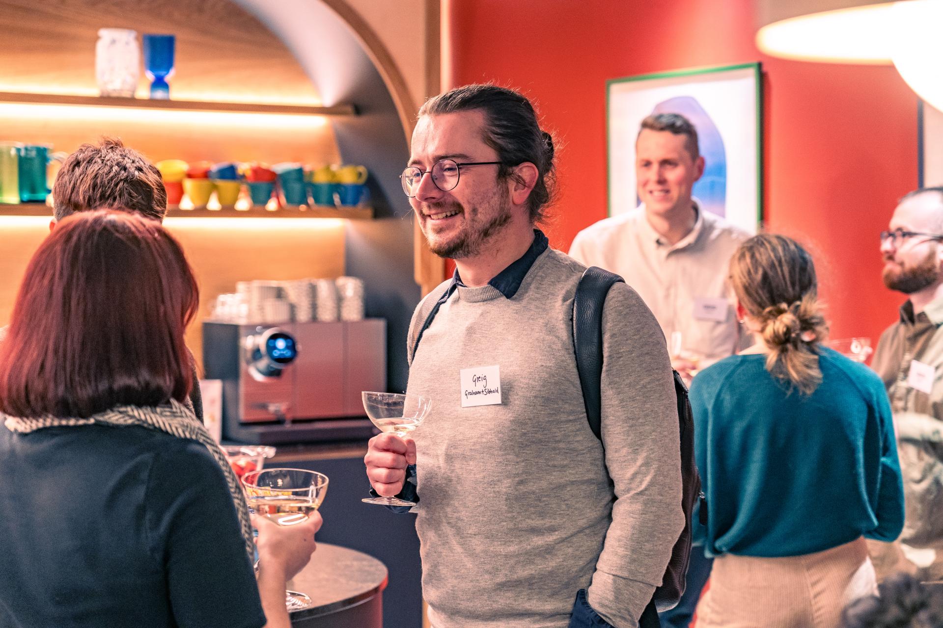 Attendees at a seminar enjoying conversation over drinks, discussing net zero carbon buildings and sustainability initiatives.