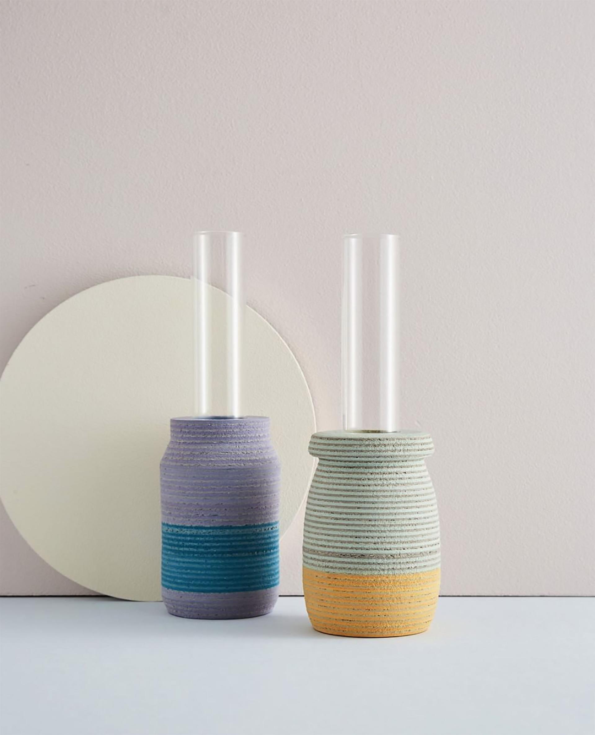 Contemporary ceramic vases with clear glass tubes, showcasing innovative design and vibrant colors, displayed against a neutral backdrop.