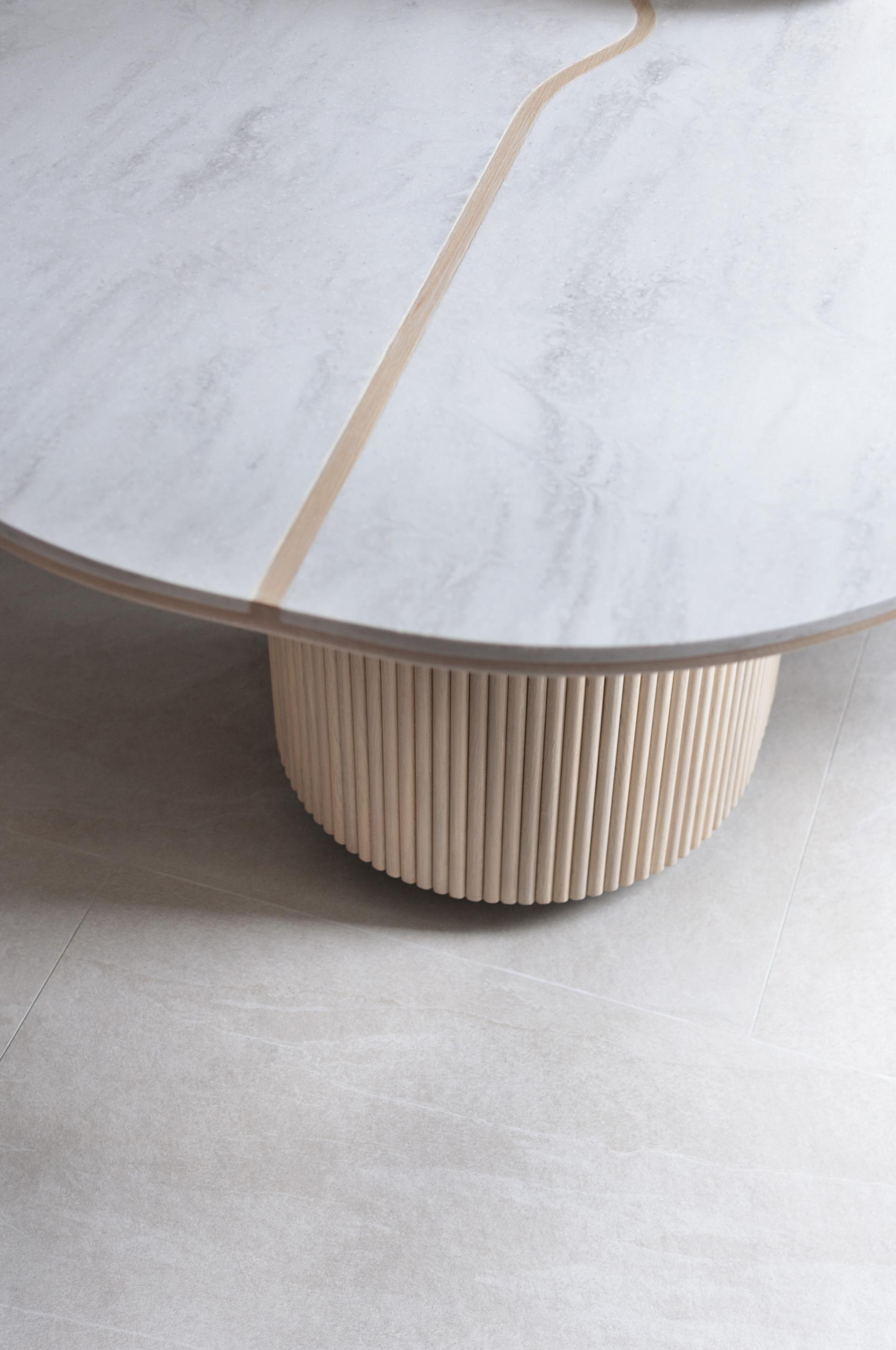 Stylish circular coffee table featuring a marble top and a ribbed wooden base, enhancing the airy design of Beau Cloud Mansion.