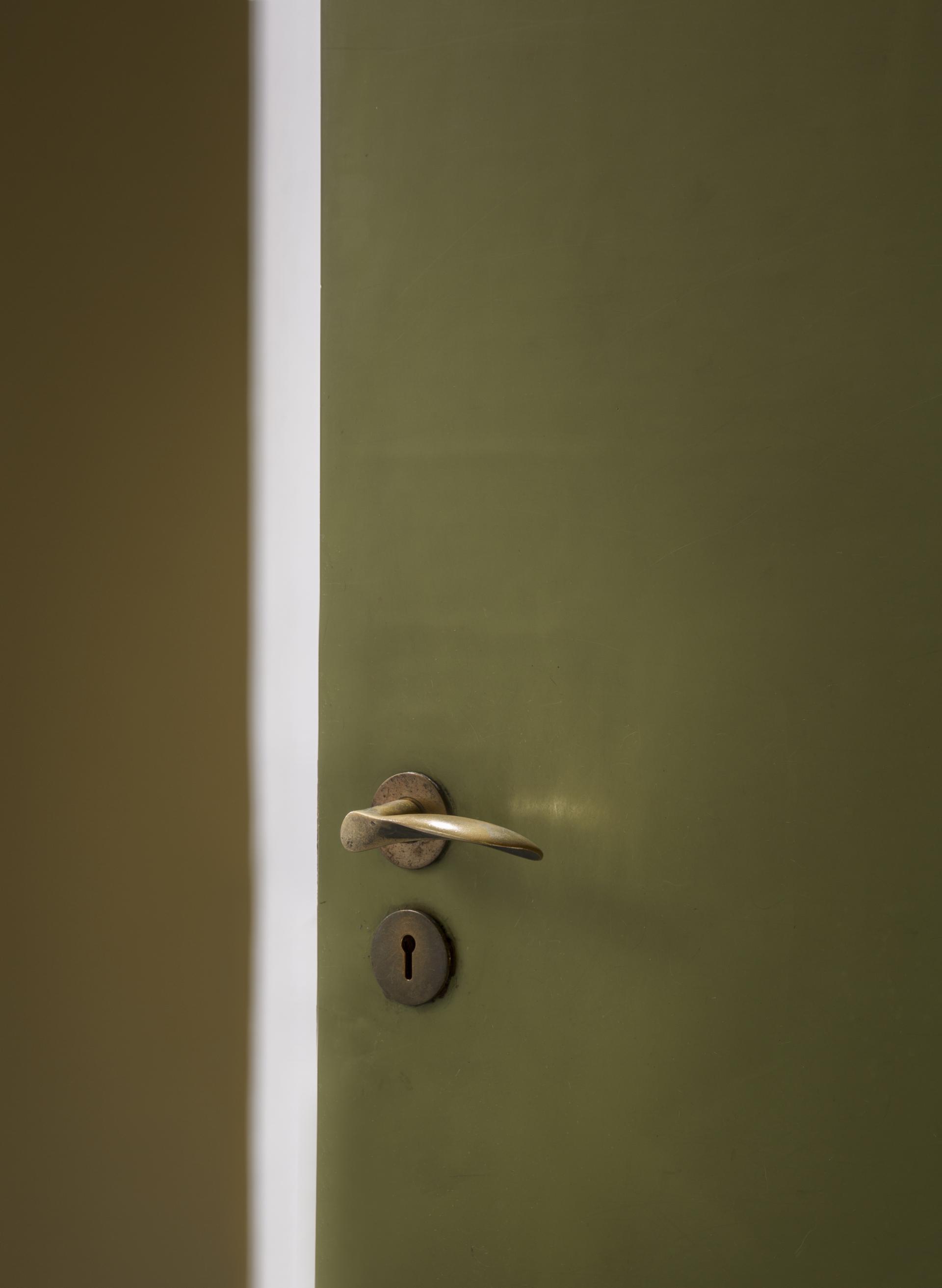 Modern green door with a brass handle and keyhole, reflecting the architectural style of St Catherine’s College, Oxford.