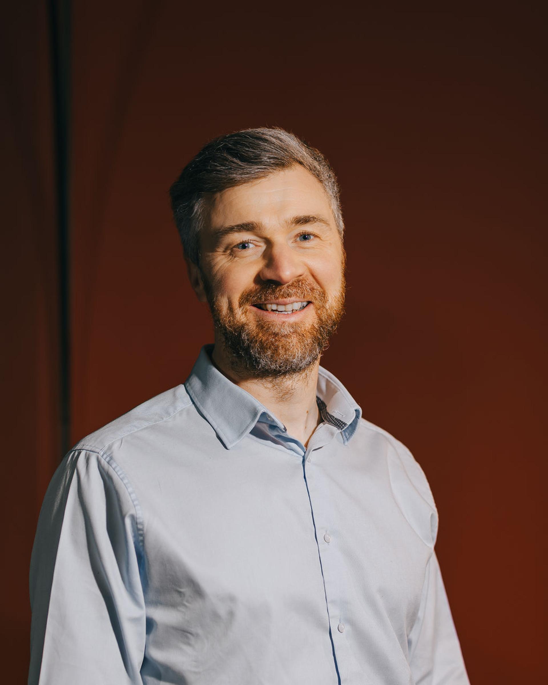 Smiling professional in a light blue shirt, emphasizing the importance of biomaterials in sustainability discussions.