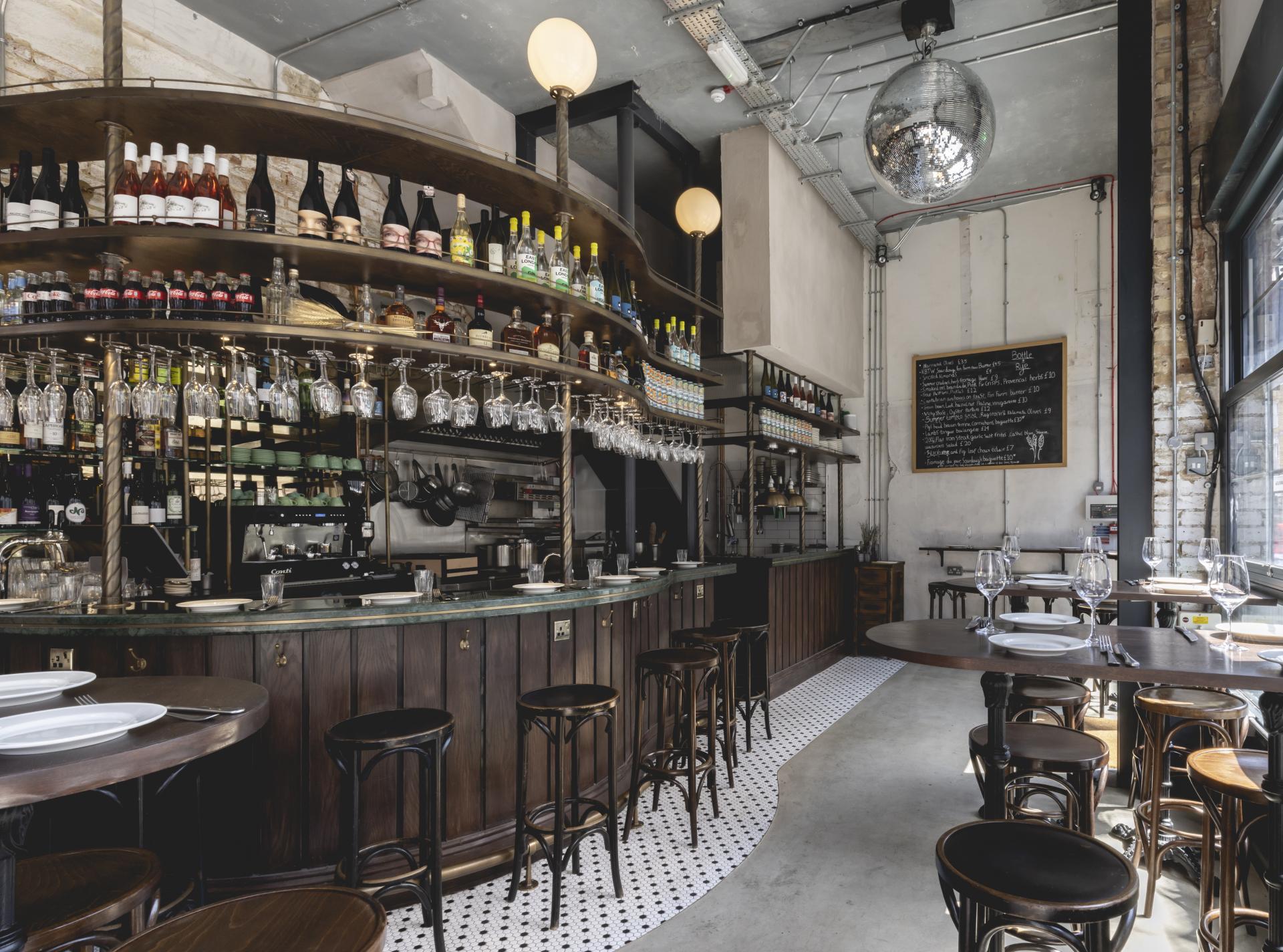 Elegant interior of Bottle + Rye wine bar featuring a curved bar, stylish seating, and a selection of beverages.