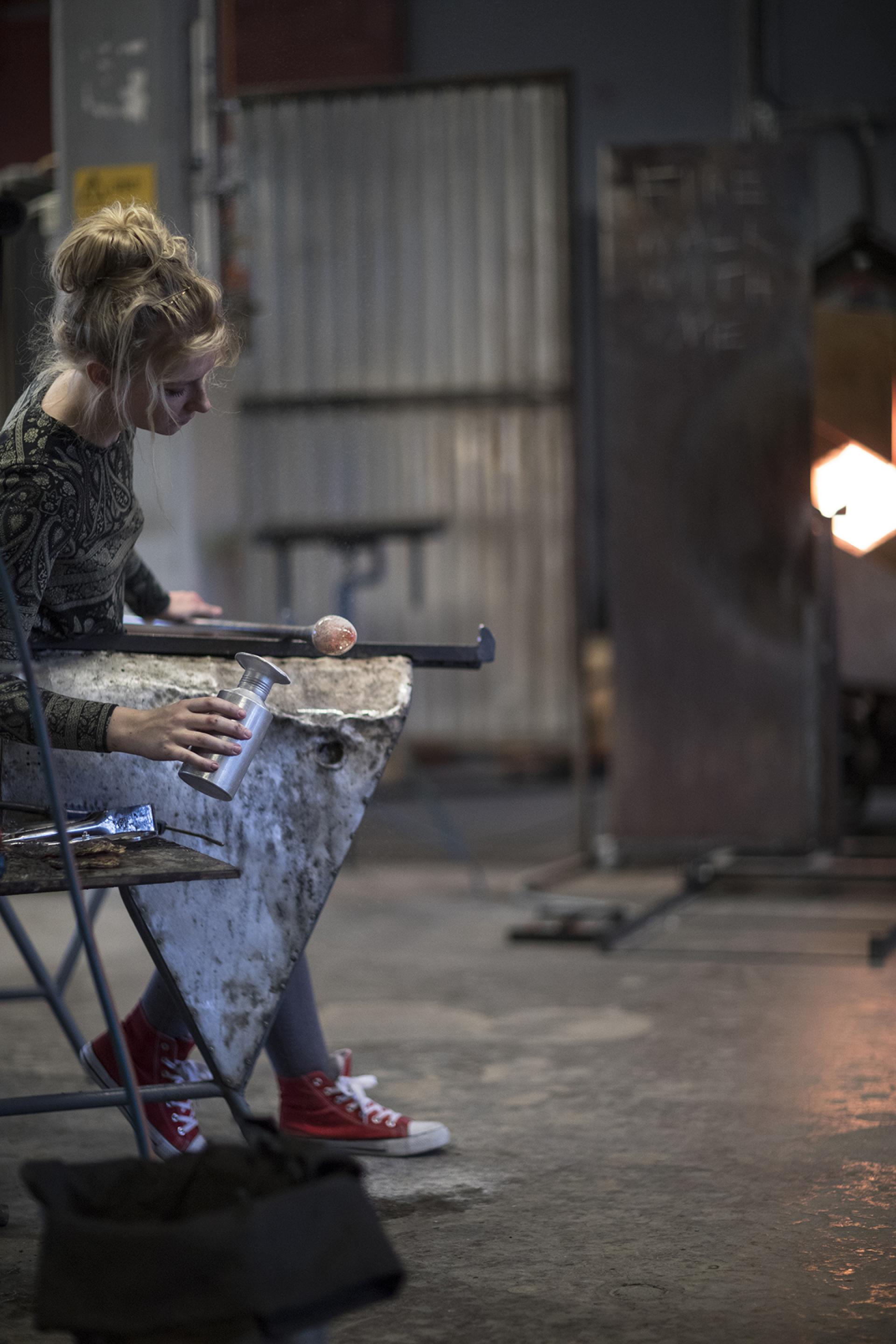 A young artisan skillfully glassblowing in the creative workshop of The Glass Factory in Småland.