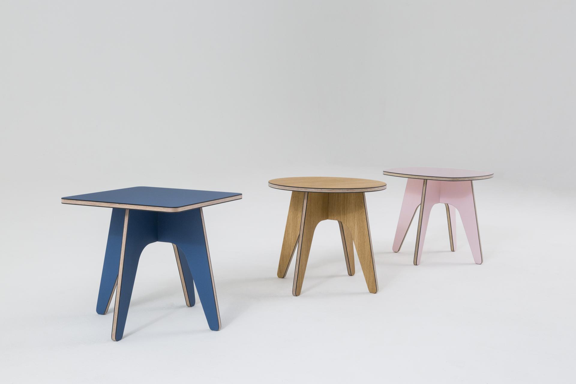 Contemporary wooden side tables in blue, natural wood, and pink showcased at designjunction on London's South Bank.