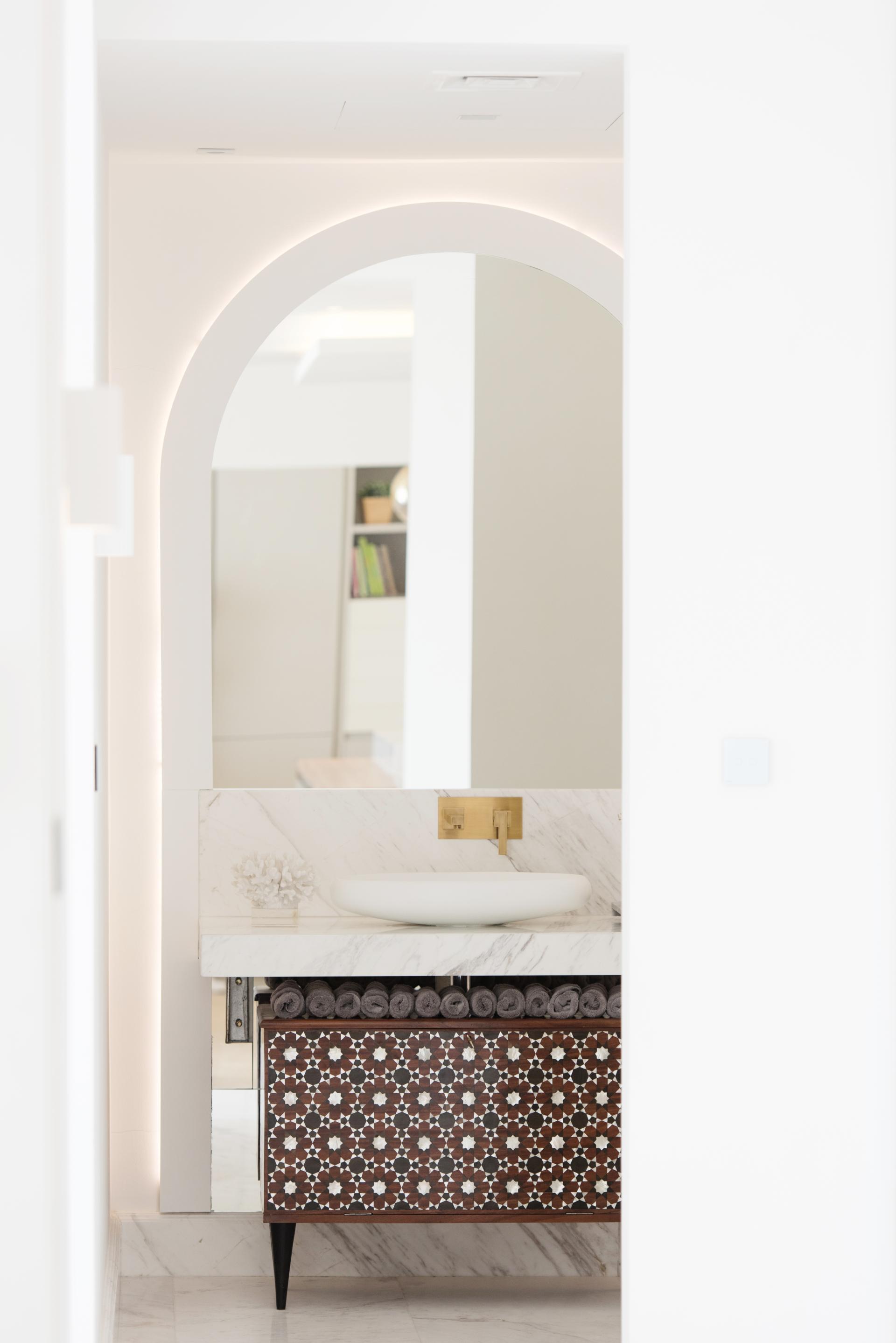 Minimalist bathroom design featuring elegant marble sink, decorative cabinet, and rolled towels, creating a serene atmosphere in Dubai.