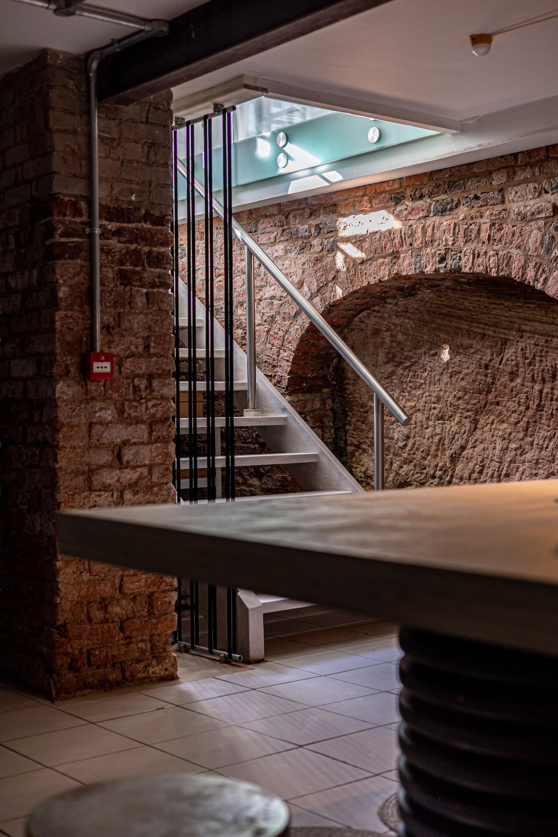 Stylish interior featuring a modern staircase, exposed brick walls, and a sleek table design by MONIKA Studio.
