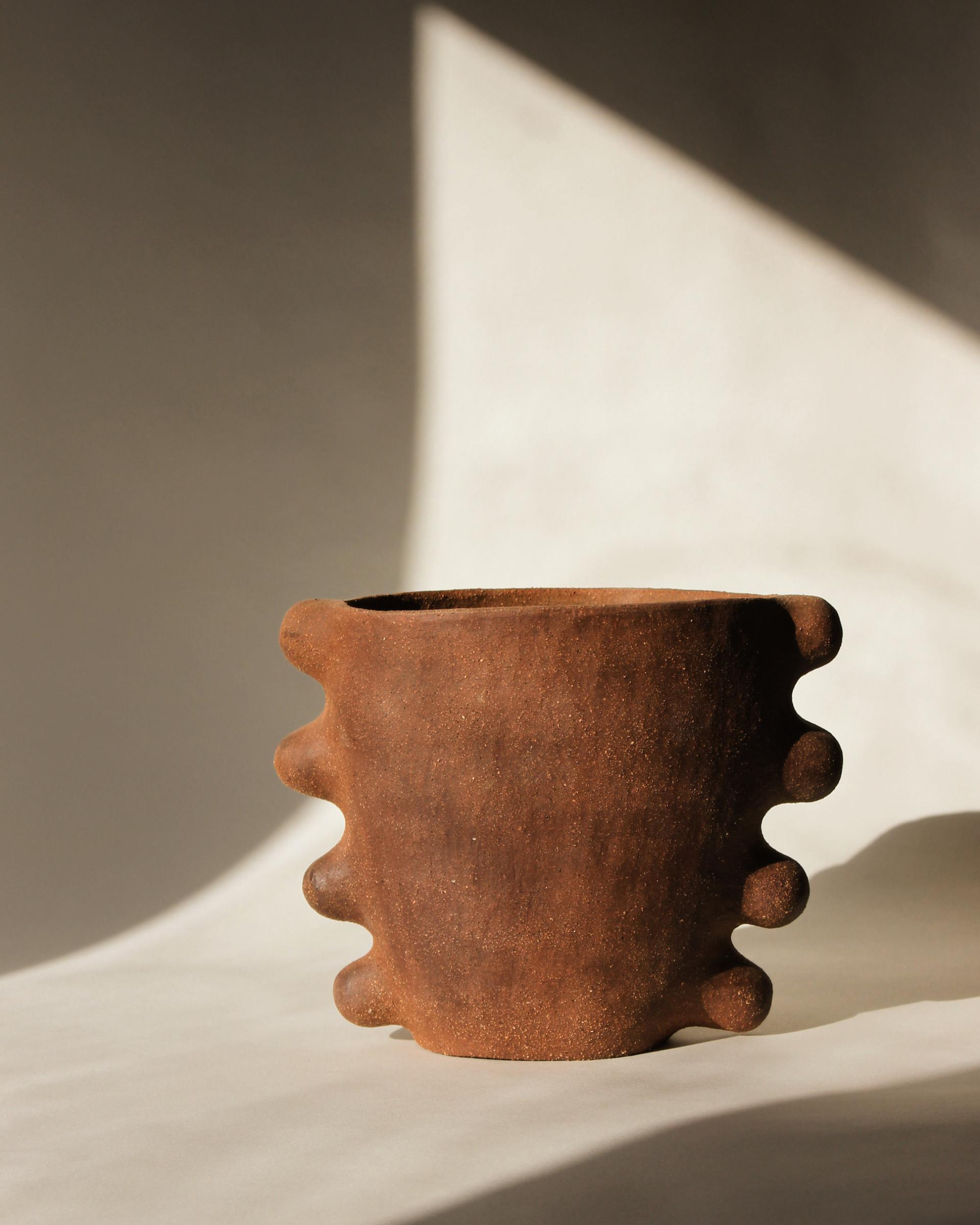 Rustic brown ceramic pot with unique tapering edges, highlighted by soft natural lighting, showcasing Glasgow's creative craft.