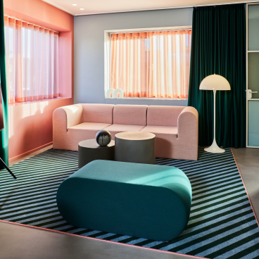 Vibrant lounge area in Kirk Suites featuring Ege Carpets' colorful striped rug and modern furnishings in Vejle.