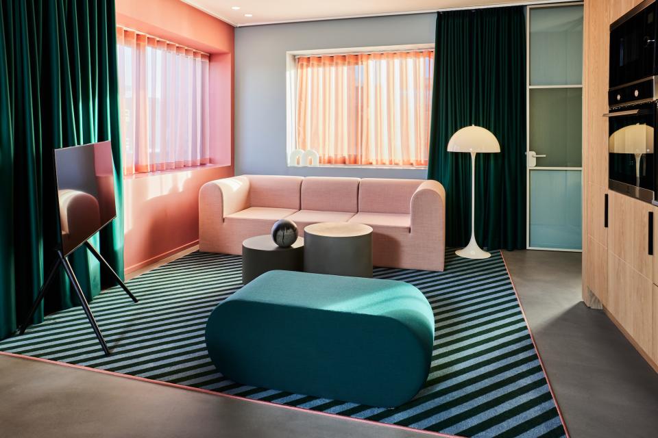 Vibrant lounge area in Kirk Suites featuring Ege Carpets' colorful striped rug and modern furnishings in Vejle.