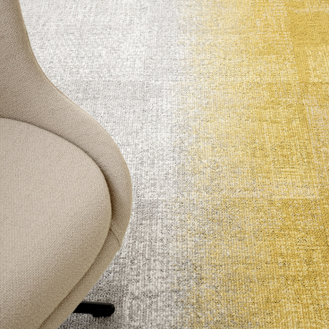 ReForm Transition carpet featuring a gradient of gray and yellow hues, accompanied by a modern beige chair.