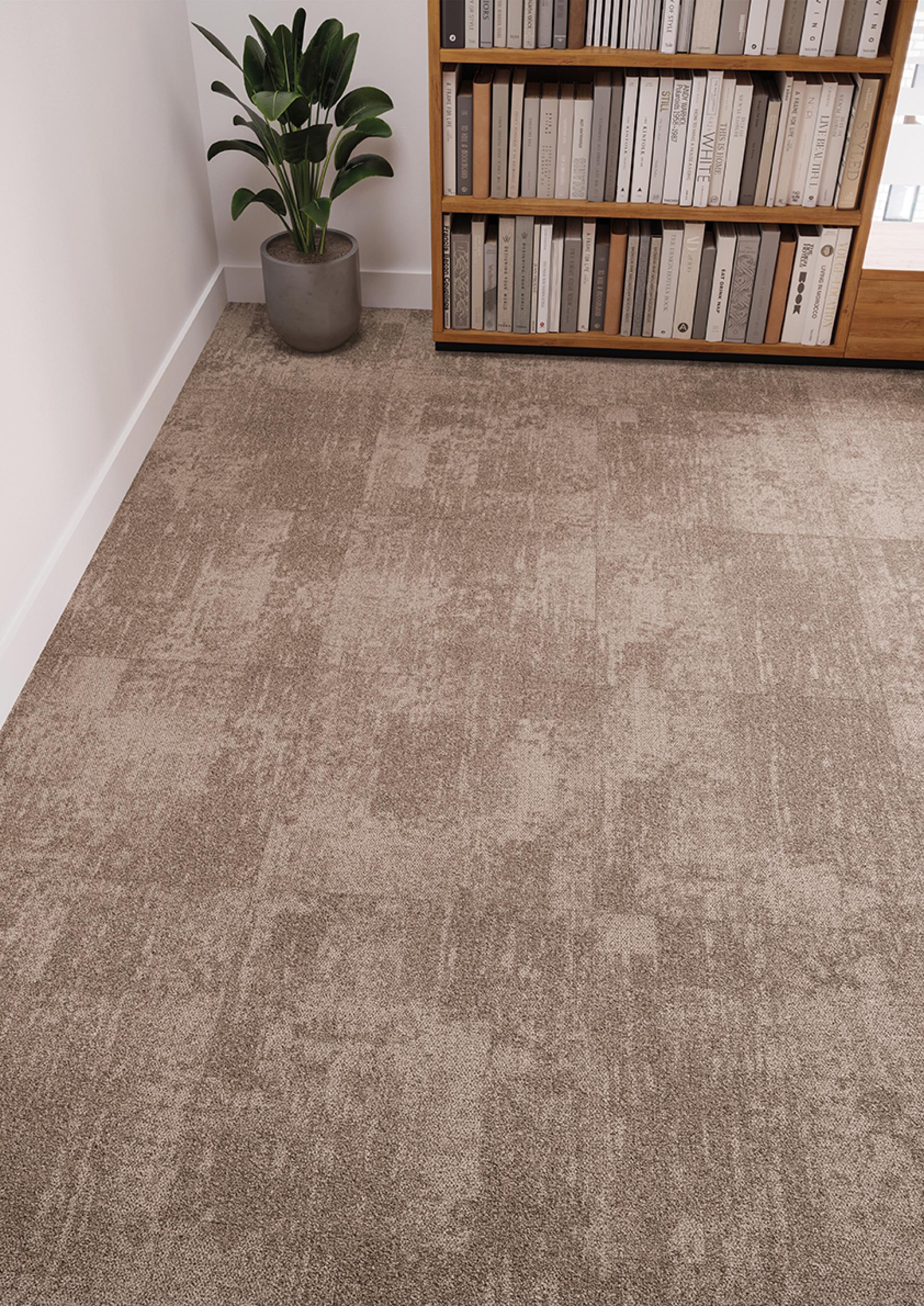 Tessera Infused carpet tiles in a modern workspace, showcasing a textured beige design and greenery in the background.