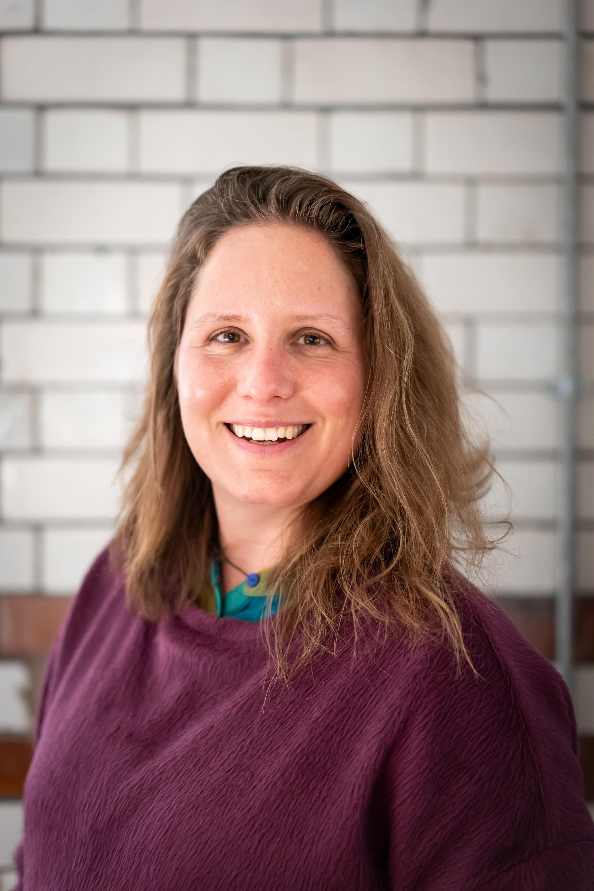 Portrait of a smiling woman in a purple sweater, embodying the themes of EDI and inclusive culture in a studio environment.