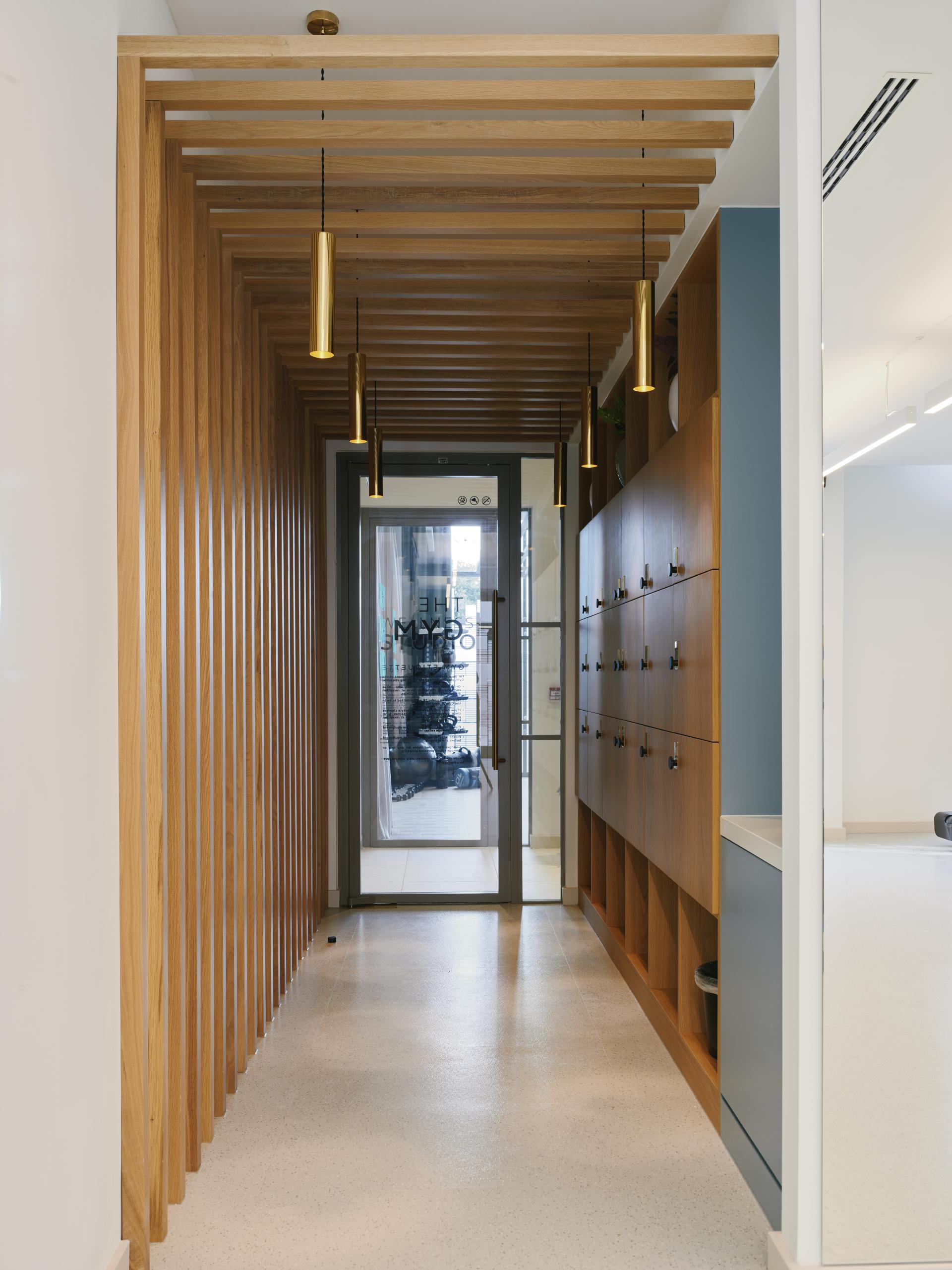 Modern entryway design featuring wooden slats, pendant lighting, and spacious lockers in The Headline residential amenity space.