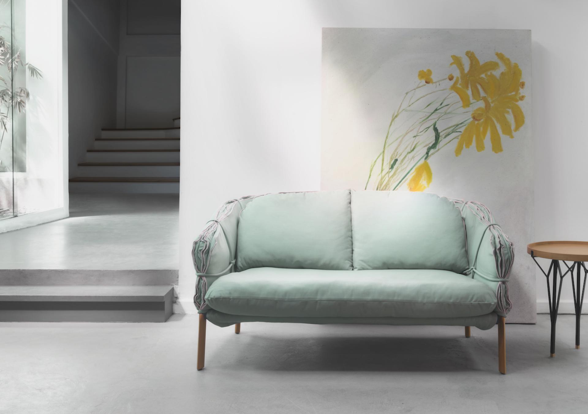 Parchment sofa by Kenneth Cobonpue, featuring elegant mint upholstery and artistic background, inspired by ancient manuscripts.