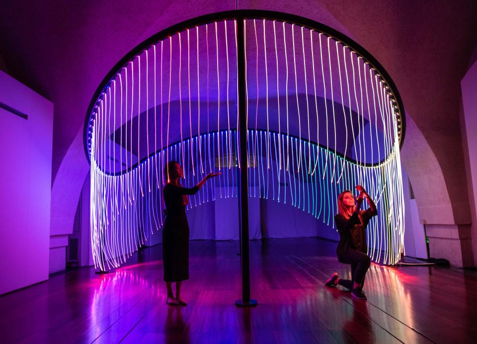 Interactive light installation at London Design Biennale featuring colorful, flowing LED strands and engaged visitors.