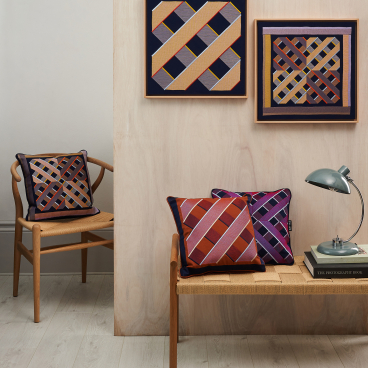 Colorful digital embroidery pillows displayed alongside framed embroidery art in a modern interior setting.