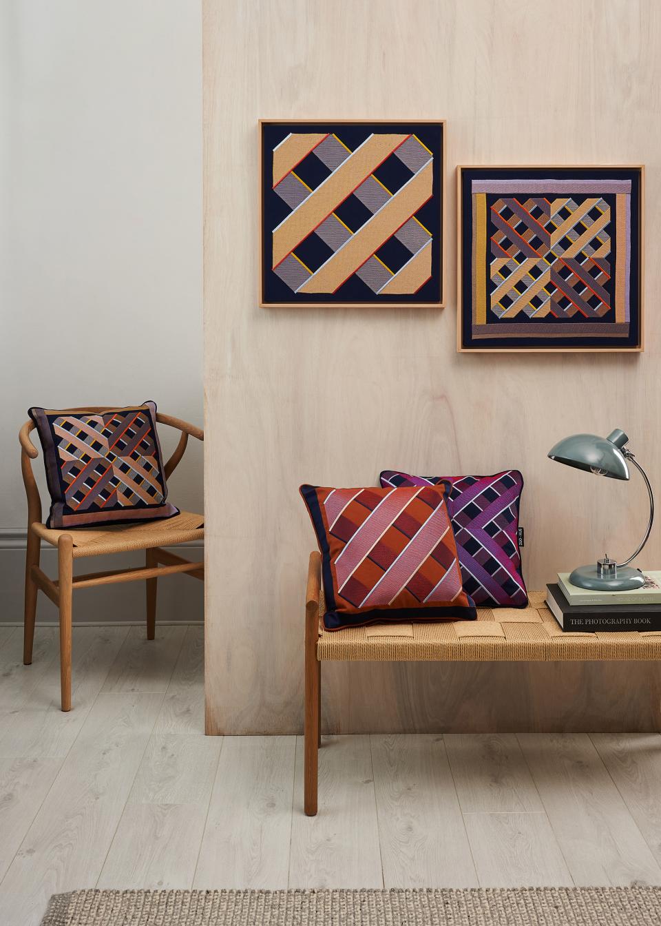 Colorful digital embroidery pillows displayed alongside framed embroidery art in a modern interior setting.