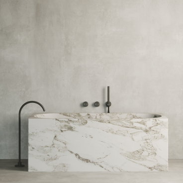 Sophisticated marble bathtub with sleek black fixtures against a minimalist concrete wall, showcasing Quadro Design Italy's new product line.