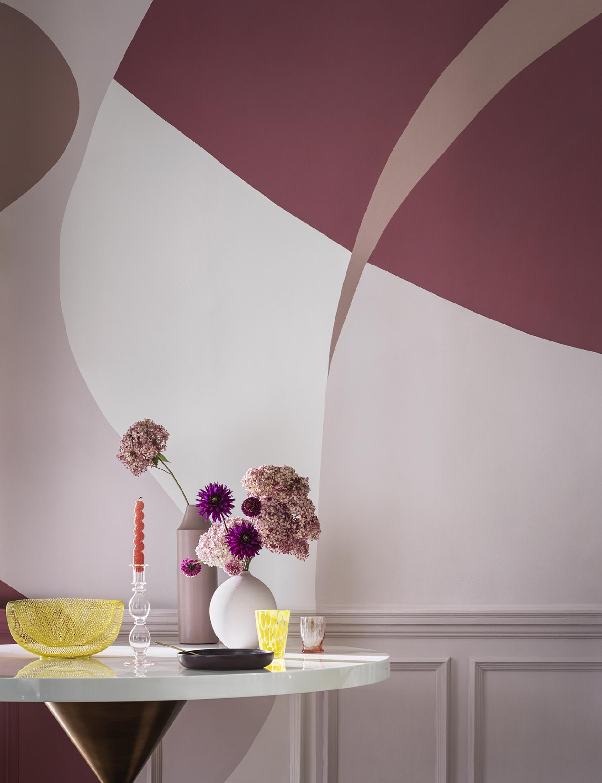 Stylish interior featuring a round table, vibrant flowers, and bold abstract paint colors reflecting SS22 trends.