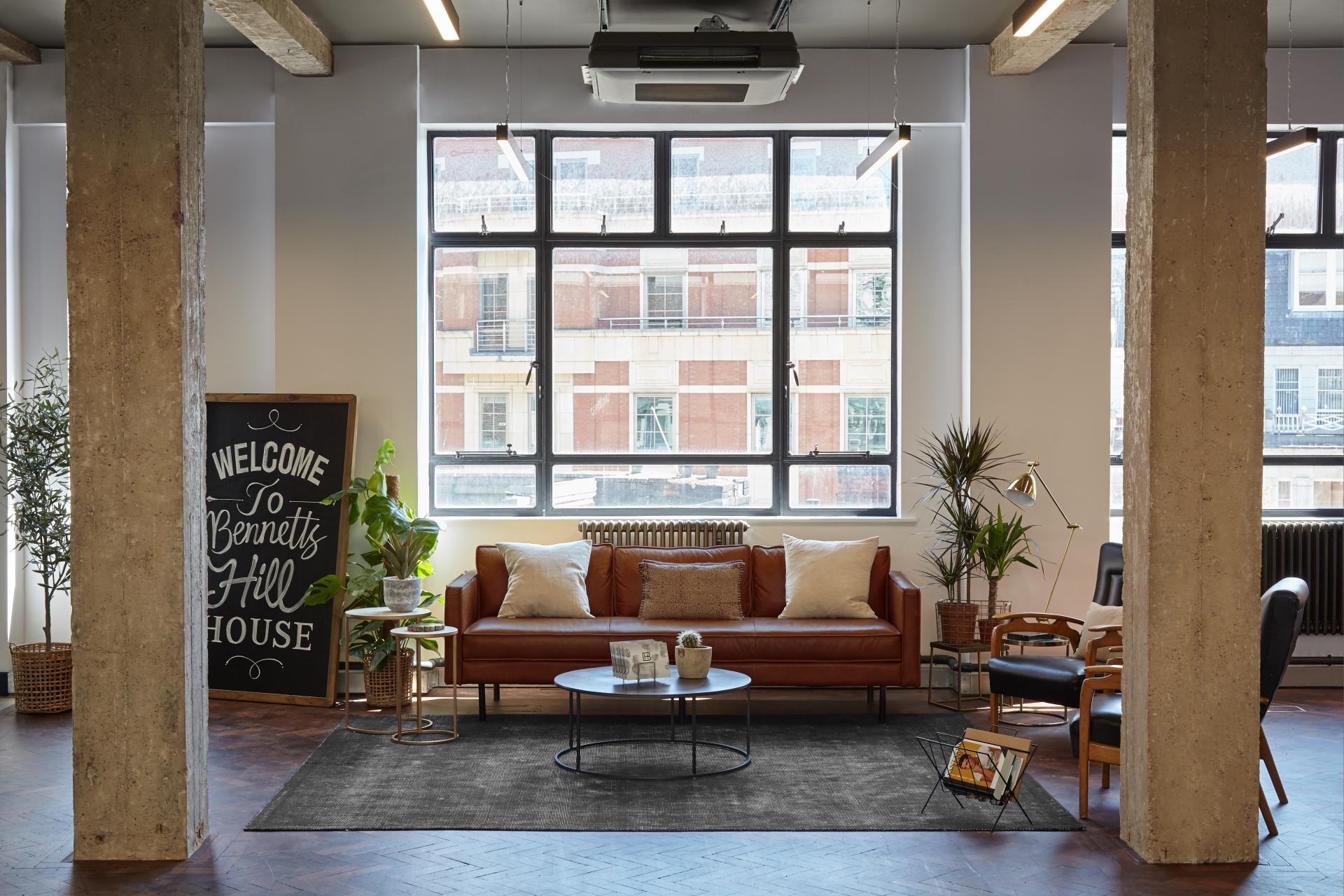 Chic loft-style office interior featuring vintage furniture, large windows, and decorative plants, designed by Run For The Hills.