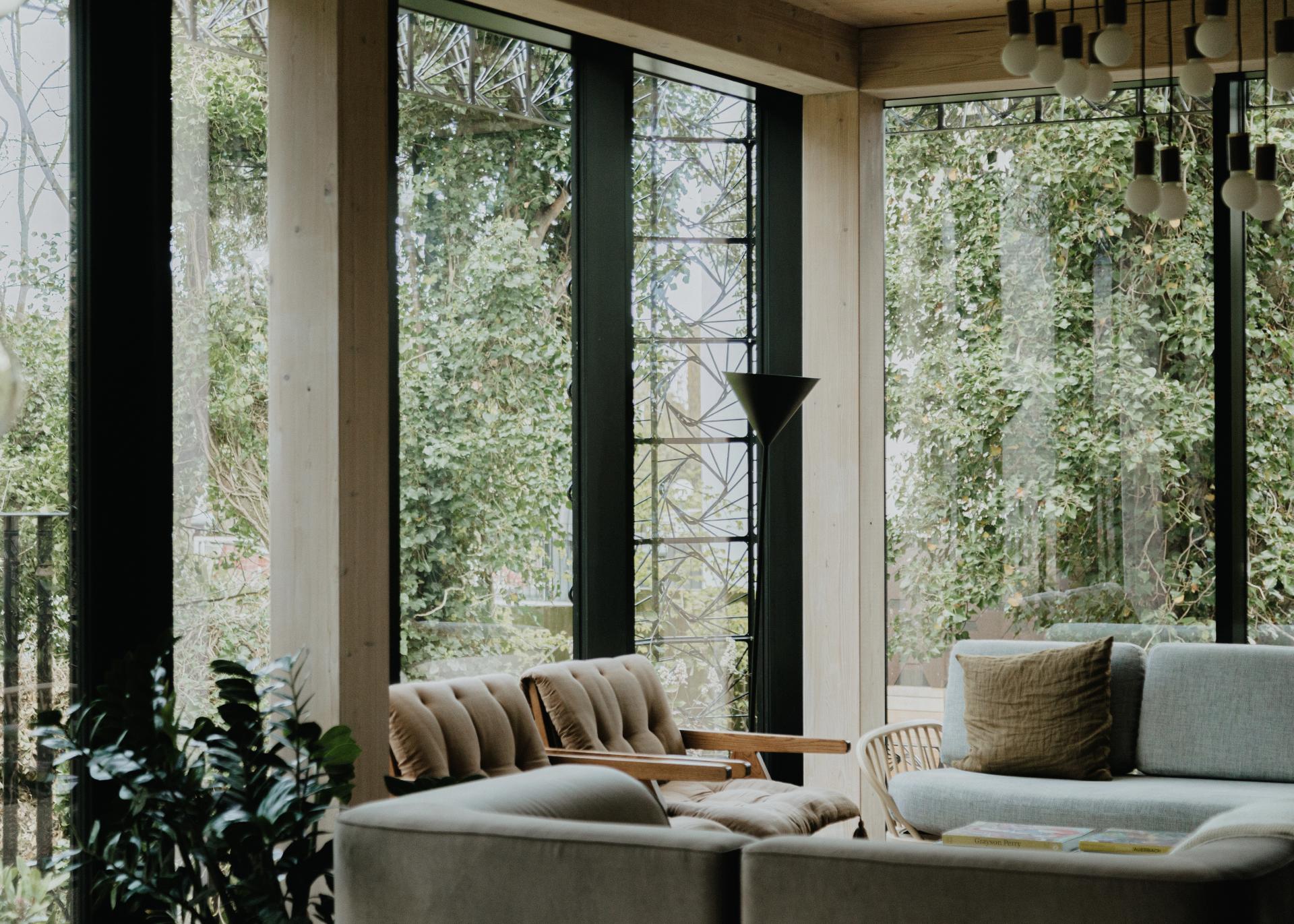 Stylish interior of a residential space featuring natural light, sculptural furniture, and views of lush greenery, reflecting Giles Miller Studio's design.