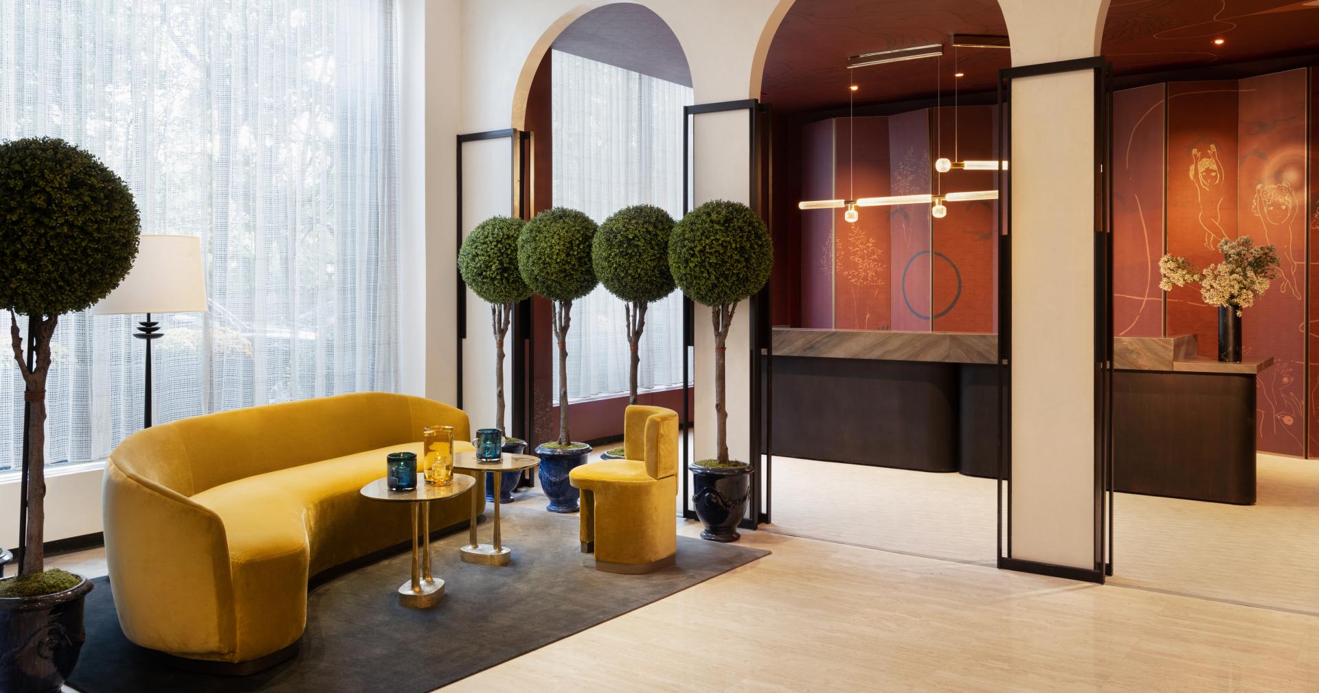 Brightly designed lobby of Park Lane New York featuring yellow seating, greenery, and artistic decor by Yabu Pushelberg.
