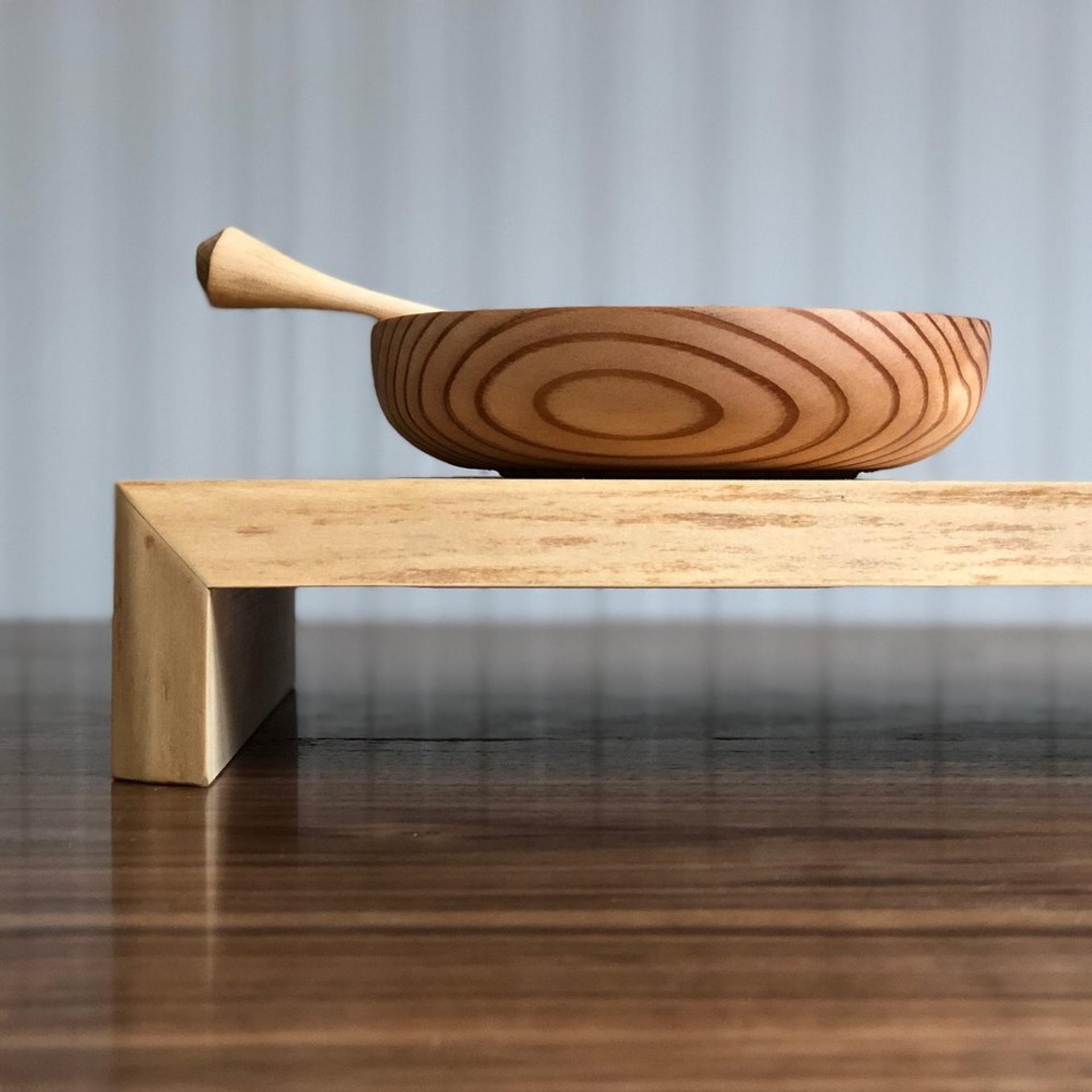 Handcrafted wooden bowl on a minimalist wooden stand, showcasing the beauty of Takumi Woodwork's craftsmanship and design influence.