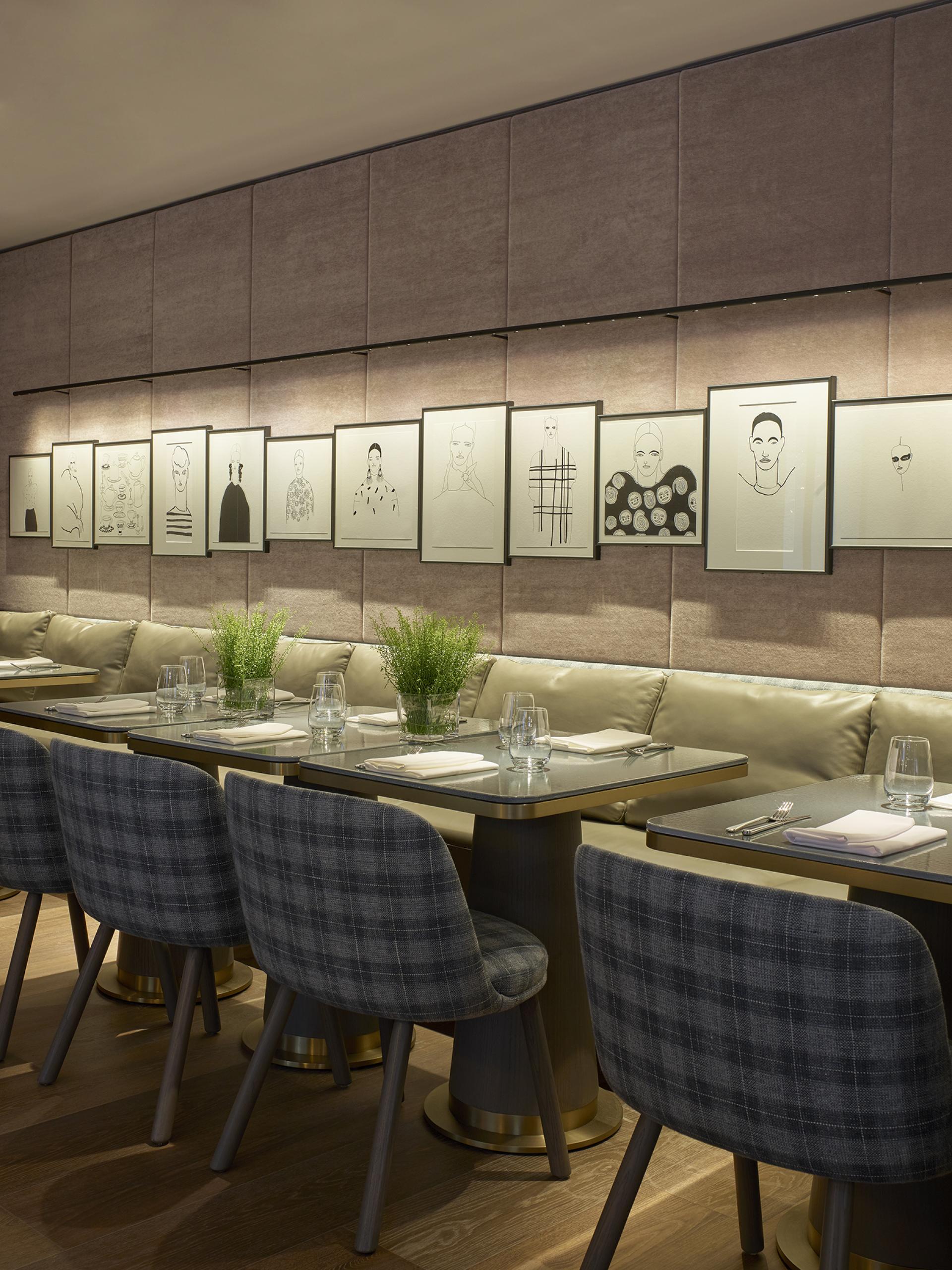 Stylish dining area featuring artistic portraits on the wall, modern tables, and upholstered seating in Leicester Square hotel.