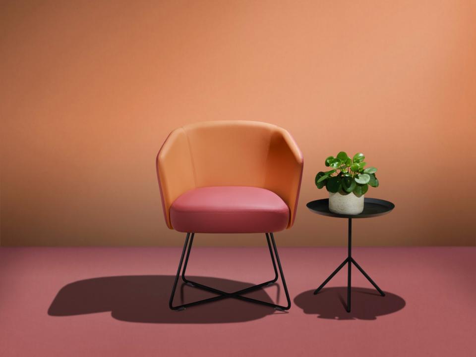 Stylish chair made with bio-based fabric, alongside a small table and potted plant, showcased at 100% Design.