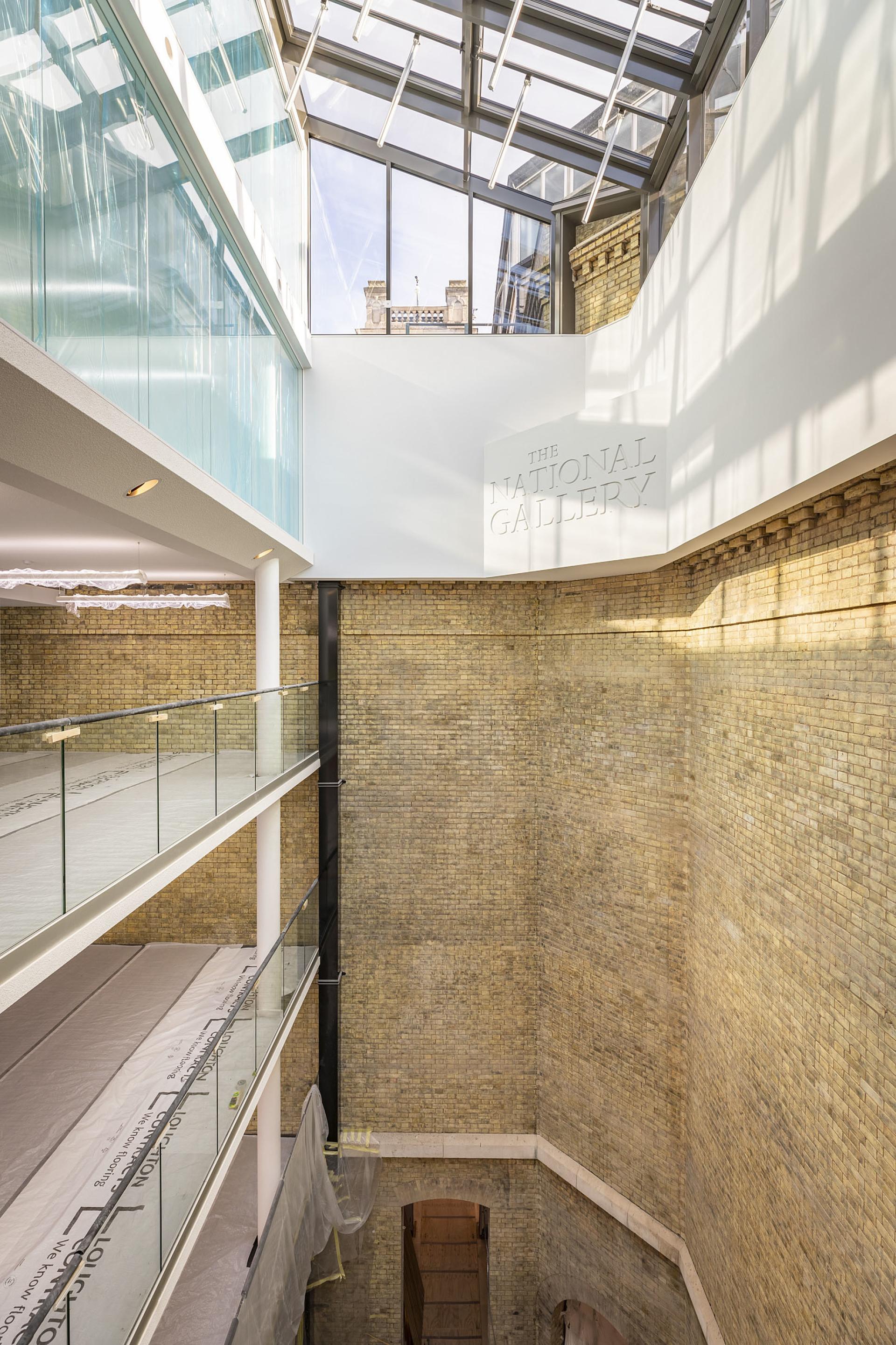 Modern interior of The National Gallery’s One Accommodation Hub, showcasing brick walls and glass architecture.