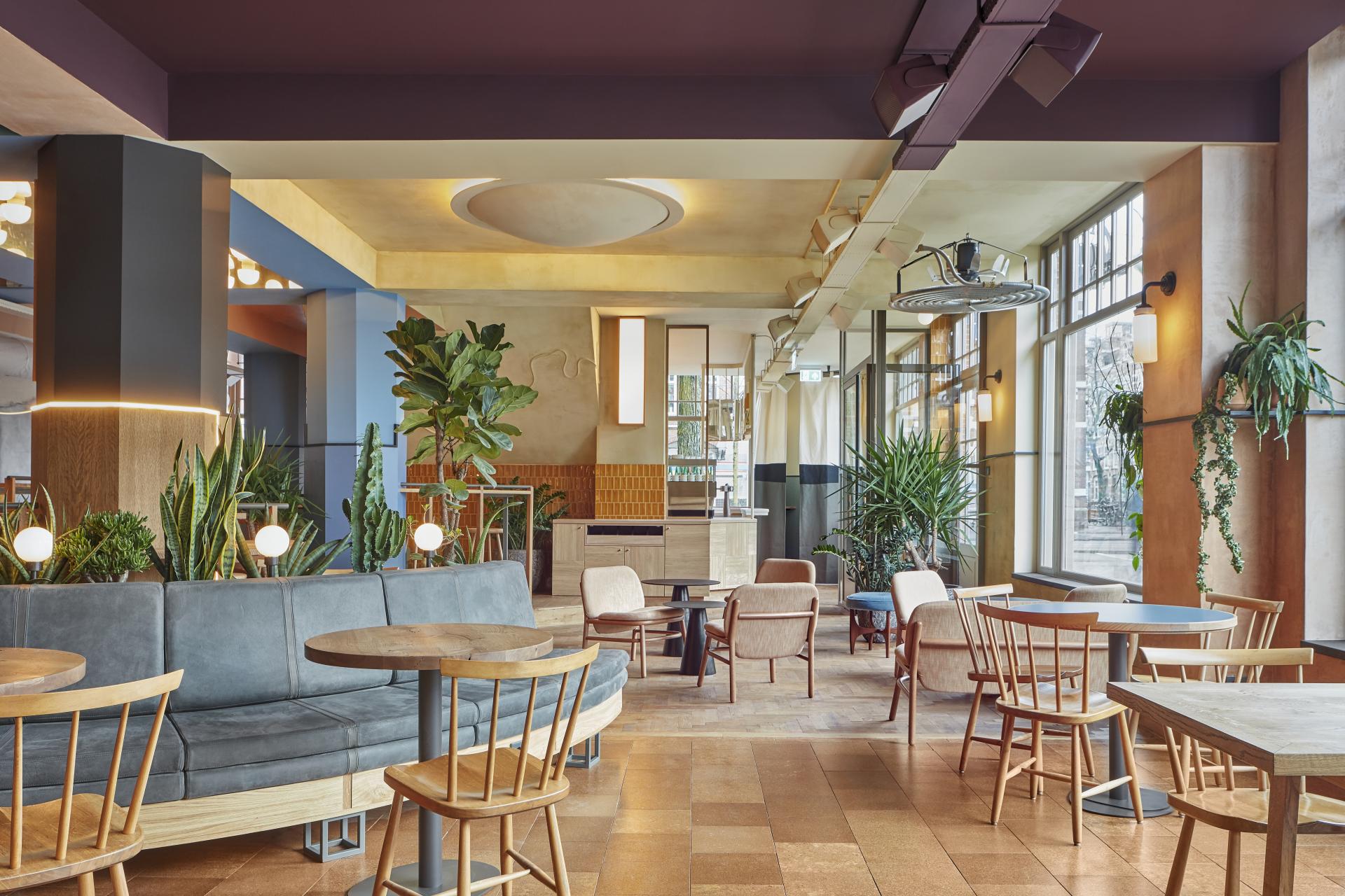 Stylish interior of Karavaan in Amsterdam, featuring cozy seating, greenery, and a welcoming atmosphere for diners.
