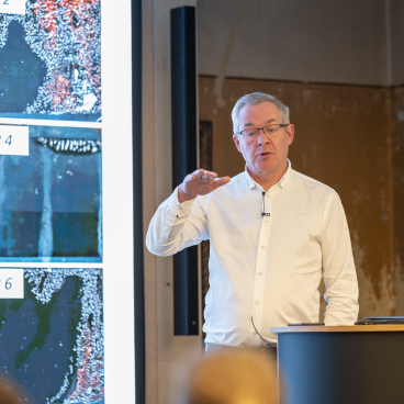 John Whittaker speaks at the Graphene Engineering Innovation Centre, presenting graphene images during a lecture on material innovations.
