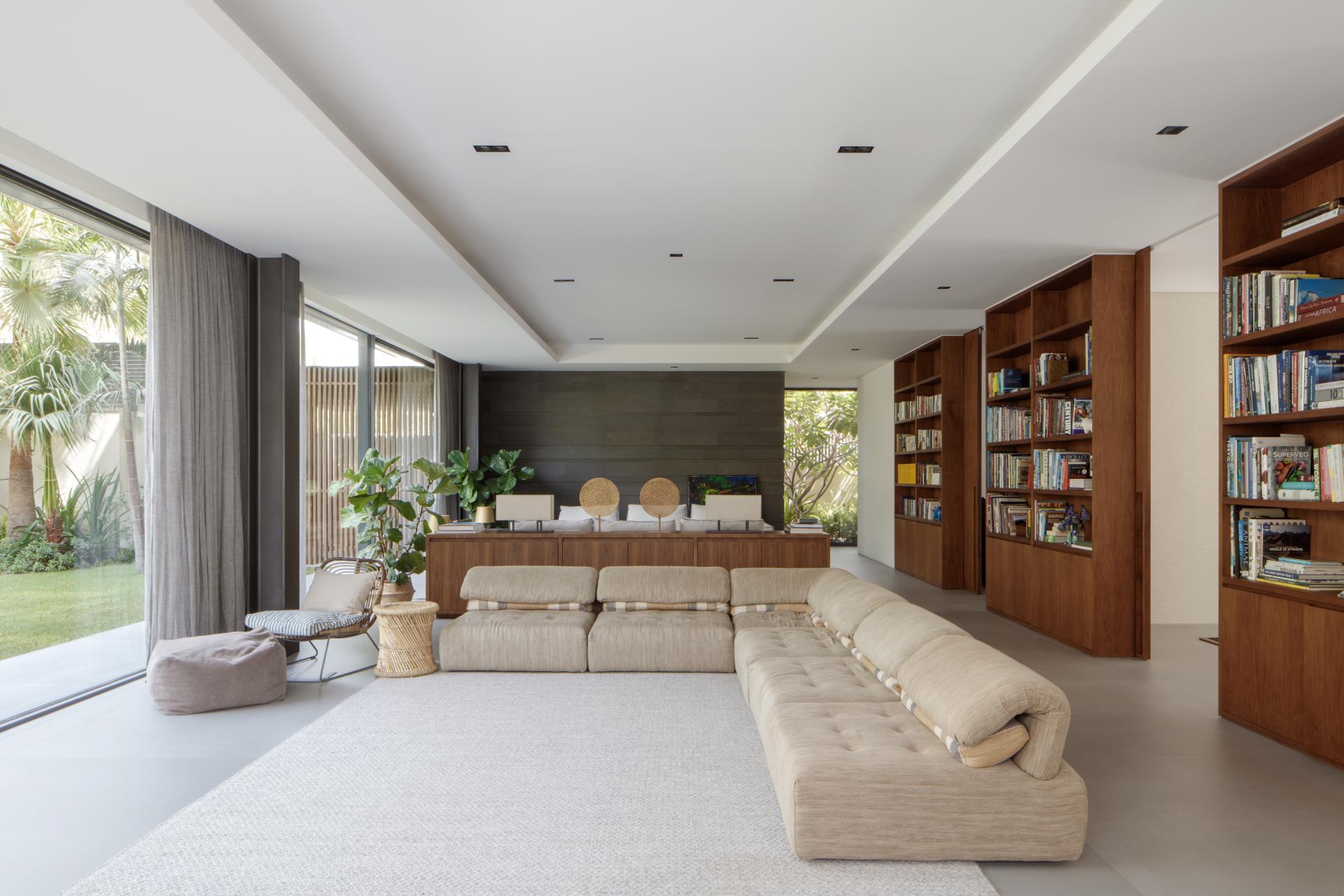 Spacious, modern living area of Villa Jumeirah featuring a cozy couch, bookshelves, and lush greenery for a tranquil atmosphere.