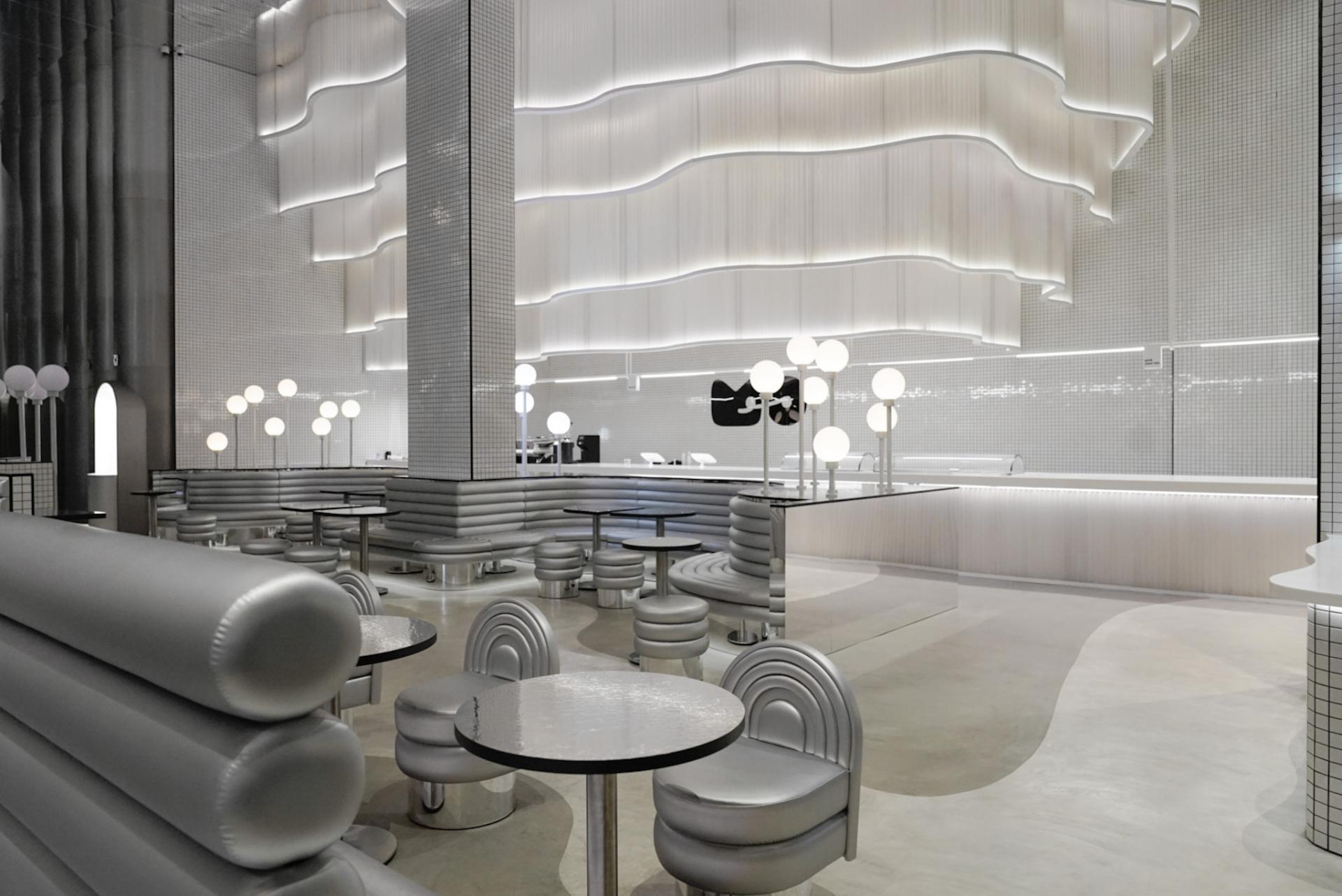 Modern interior design of MO bakehouse and espresso bar in Khobar, featuring sleek silver furniture and ambient lighting.