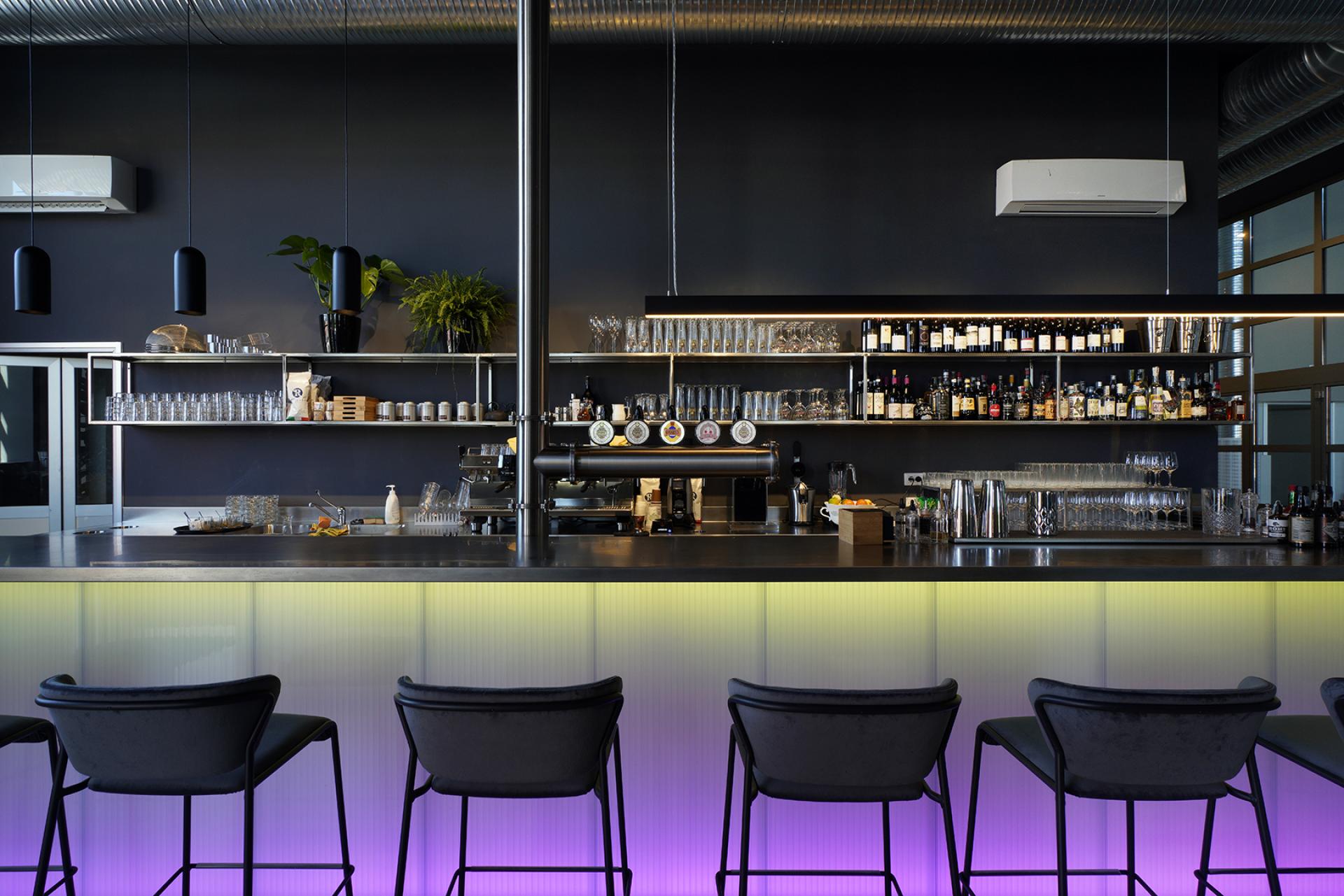 Stylish bar area in a transformed power plant, featuring modern design, vibrant lighting, and a selection of drinks.