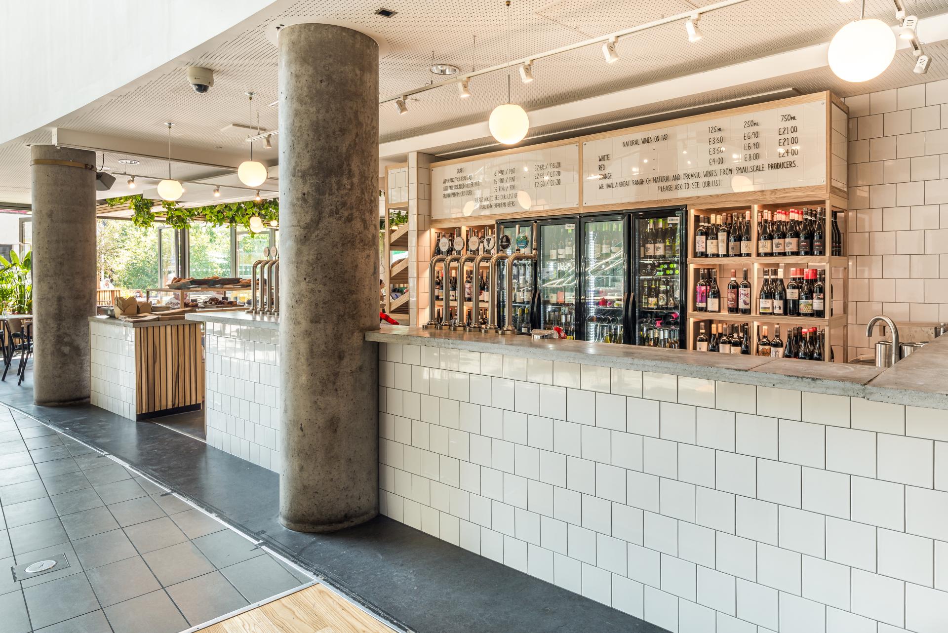 Modern café interior of Bristol Loaf at Bristol Beacon, featuring a stylish bar, drinks display, and vibrant greenery.
