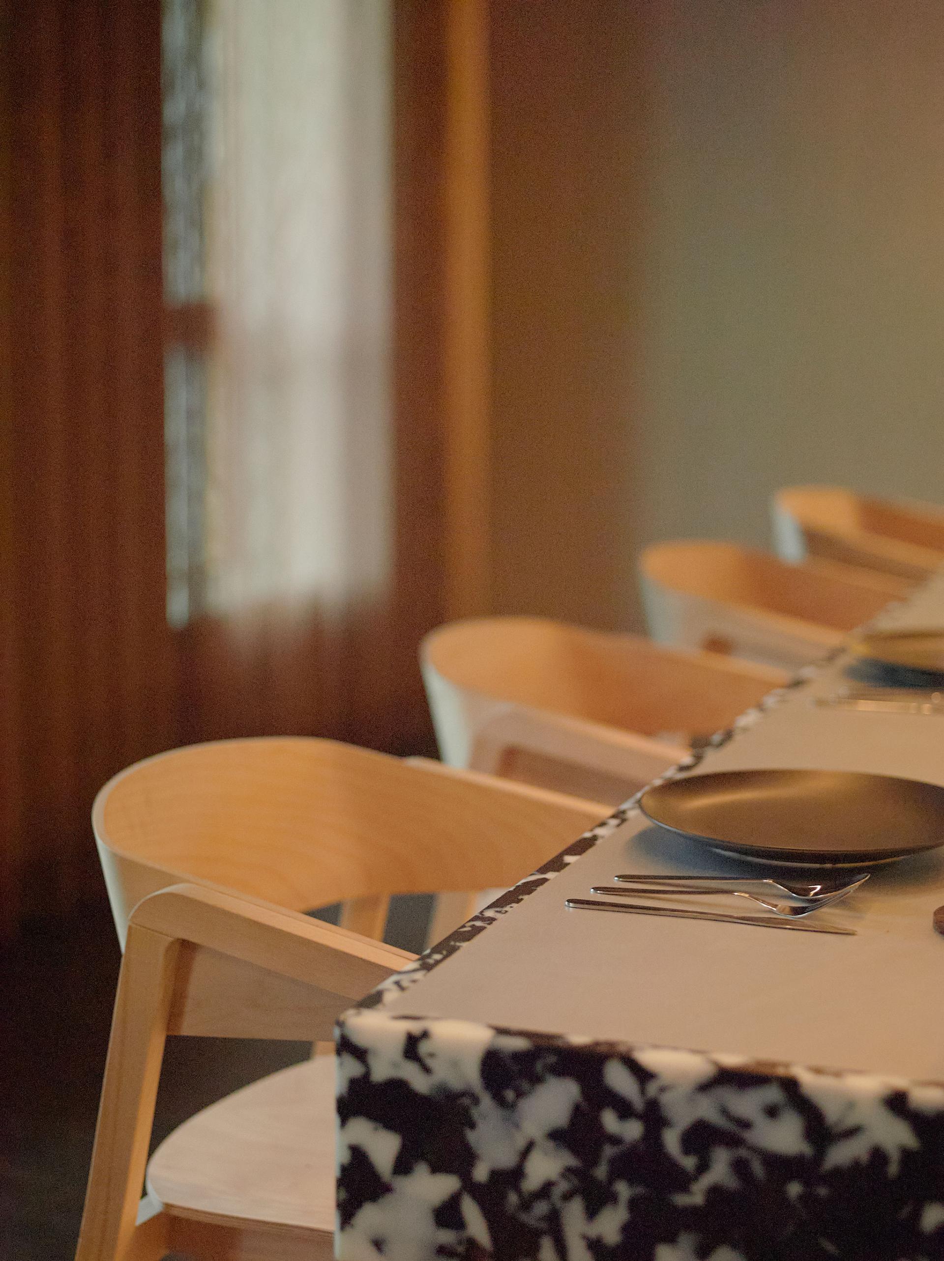 Modern dining setup with minimalist wooden chairs and elegant tableware at 16-18 Potterrow, Edinburgh PBSA interior.